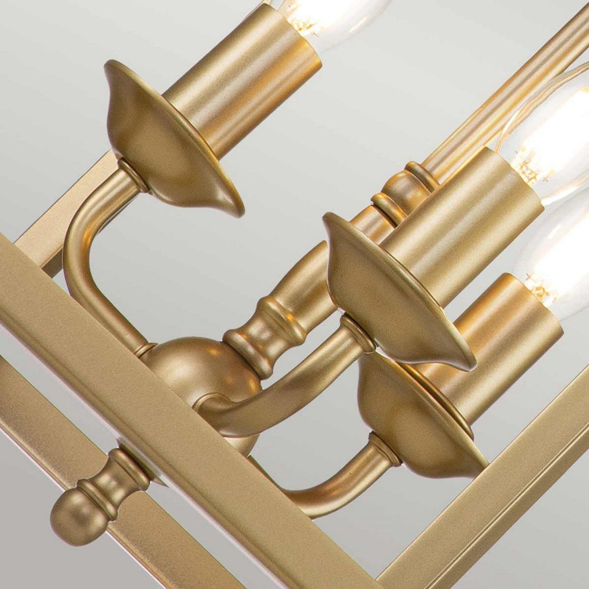 The Larkin 3 Light Medium Chandelier in natural brass showcases a gold finish with several candle-style bulbs. Its elegant metal arms support the bulbs, blending classic style with an open cage design for timeless appeal.