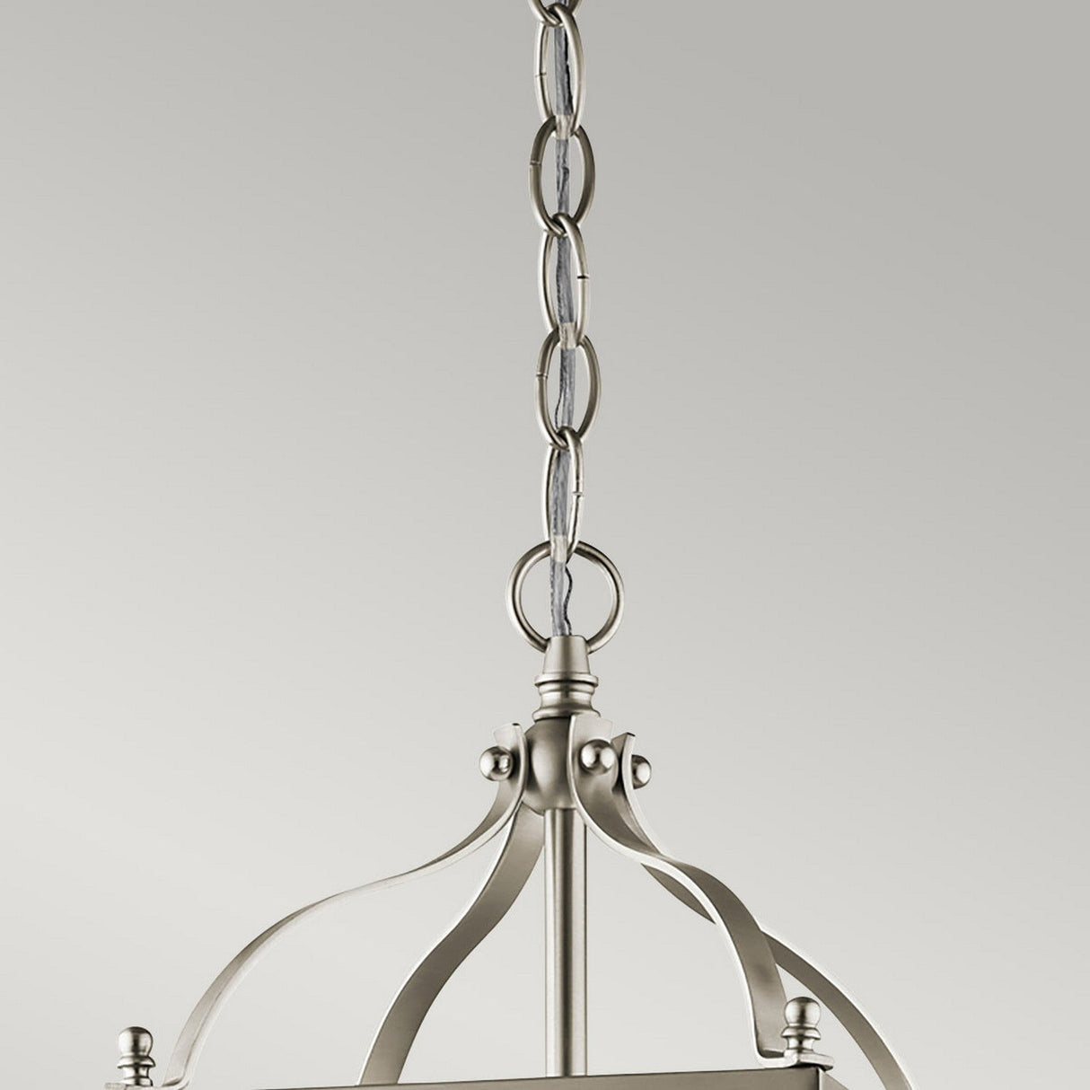 Close-up of the Larkin 2 Light Small Chandelier in brushed nickel, showcasing its open cage design. The decorative chain links to a smooth, curved frame set against a neutral background.