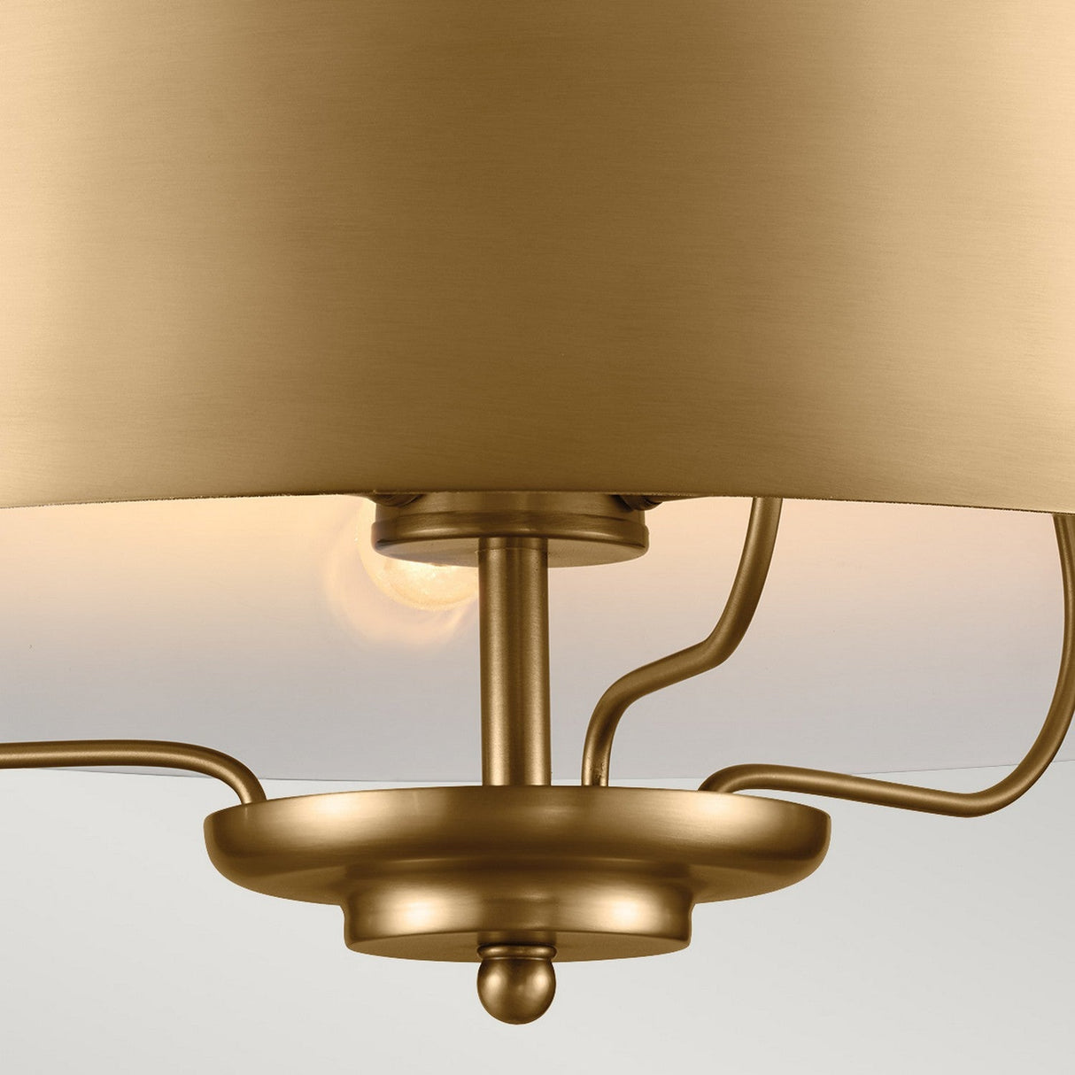 Close-up of the Luella 3 Light Duo-Mount Chandelier/Semi-Flush in brushed natural brass, showcasing a smooth, round base and gracefully curved symmetrical arms. The bulb emerges from beneath a wide, shallow shade, providing a warm glow to this elegant lighting solution.