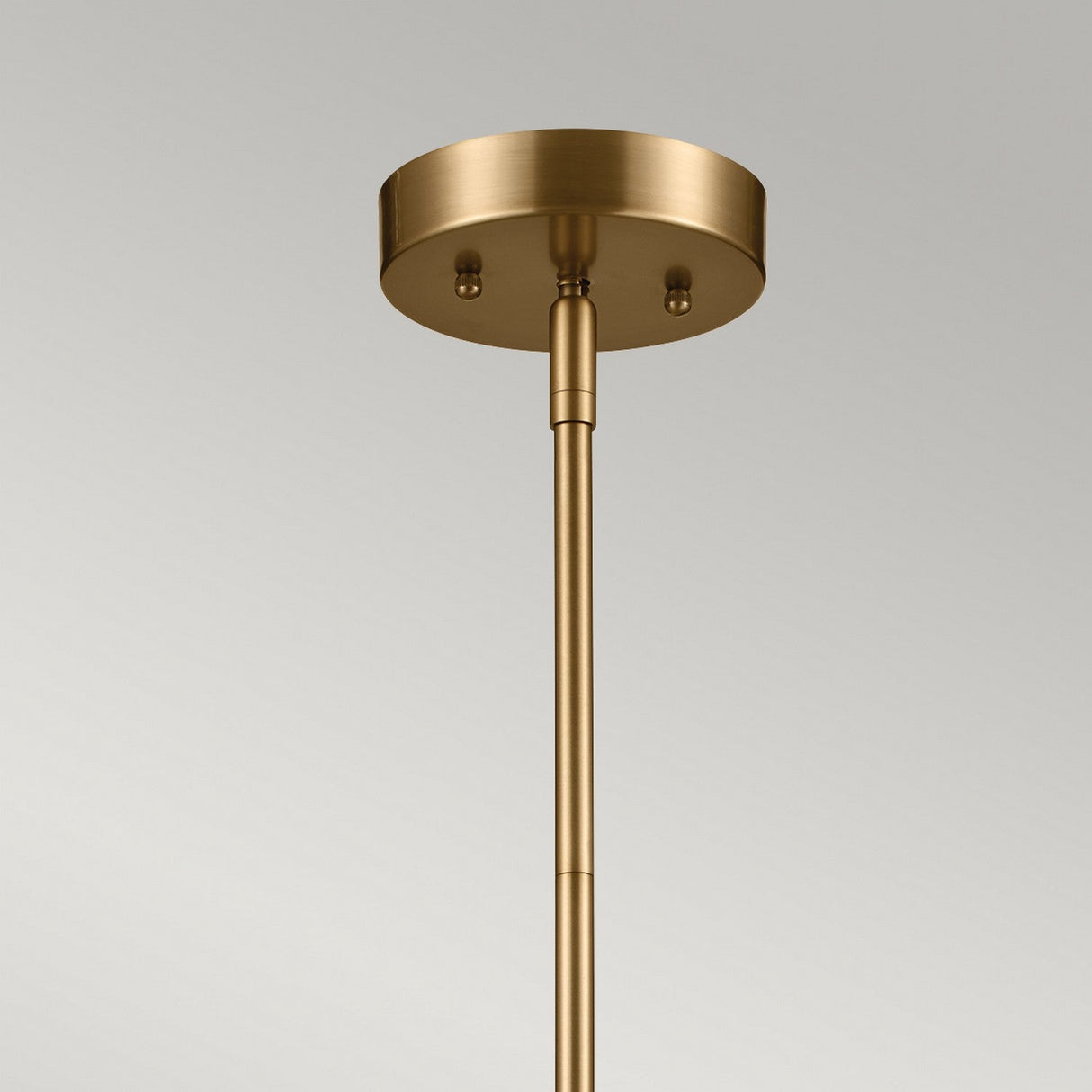 A close-up of the Luella 4 Light Duo-Mount Chandelier/Semi-Flush in Black & Brass showcases its modern brass finish, featuring a versatile duo mount design with a round, metallic base and slender rod set against a plain gray background.