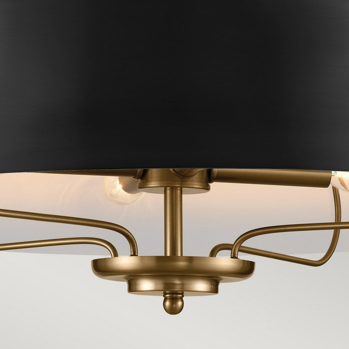 Close-up of the Luella 4 Light Duo-Mount Chandelier/Semi-Flush in Black & Brass, featuring a brass ceiling light fixture with a sleek black shade. Partially visible exposed bulbs are artistically arranged on gracefully curved metal arms extending from the center. The blurred neutral-toned background accentuates its sophisticated black and brass elegance.