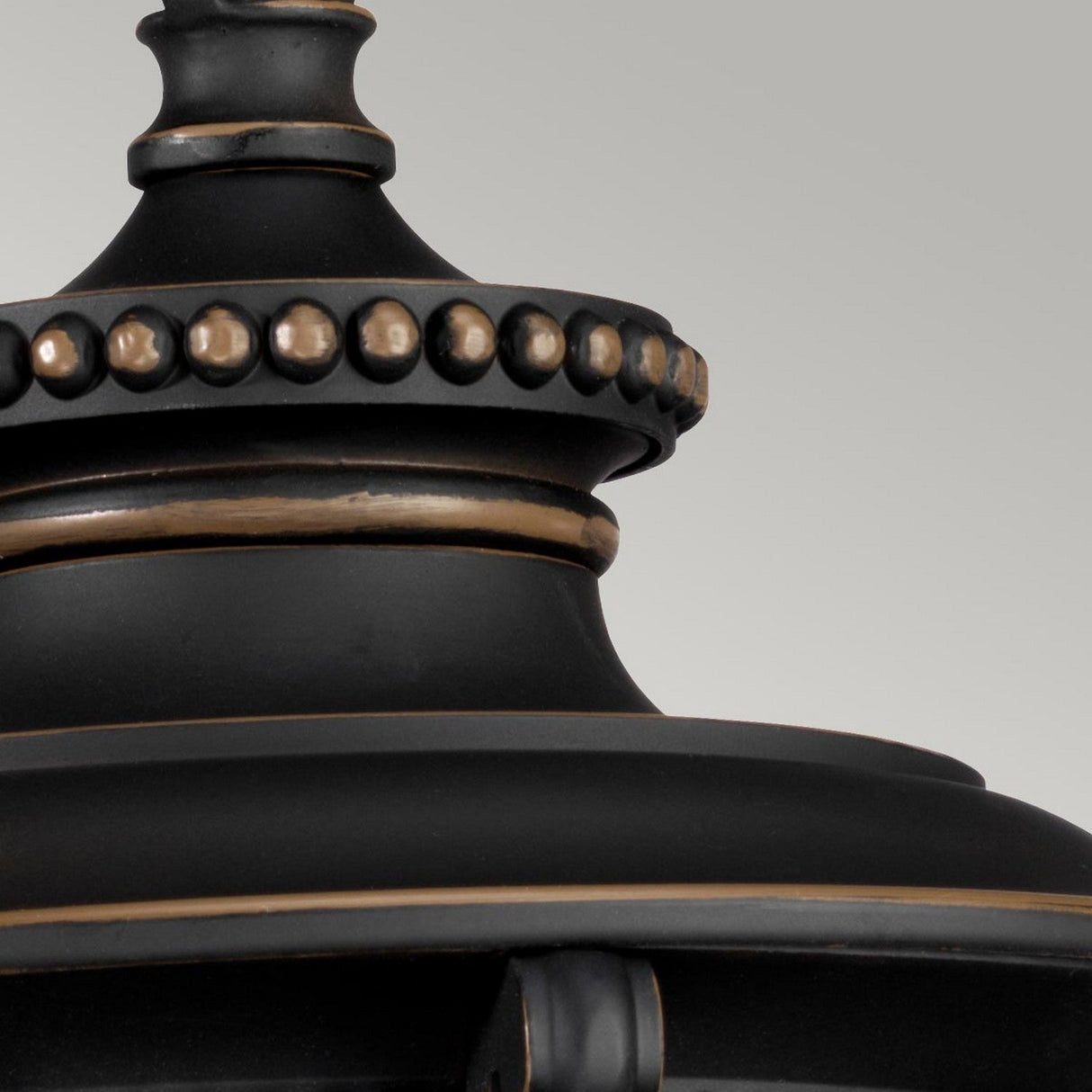 A close-up view of the Luverne Outdoor 1 Light Medium Chain Pendant, showcasing its black metal with an oil-rubbed bronze finish, adorned with decorative gold accents and a beaded detail near the top, set against a plain gray background.