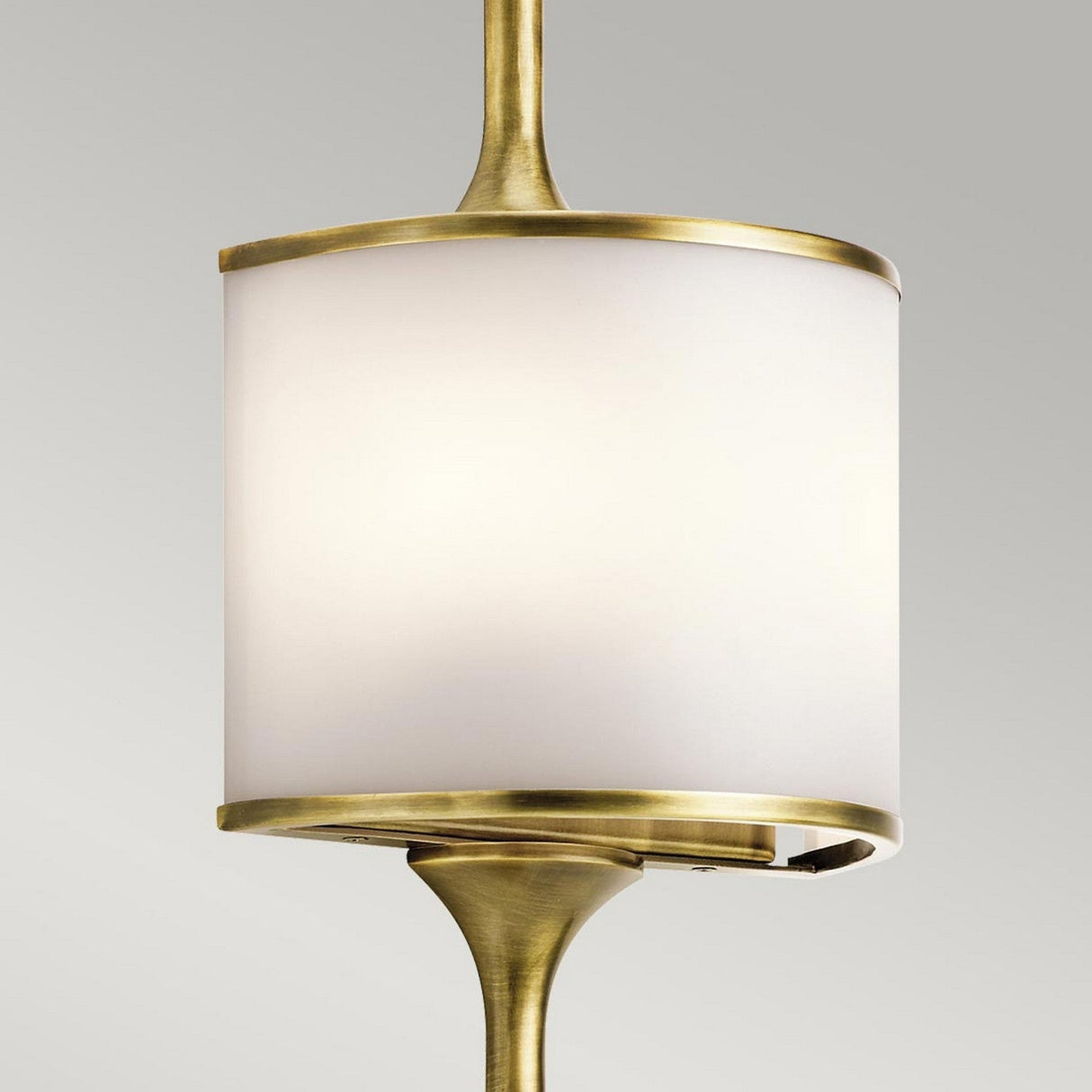 Against a light gray background, the Mona 2 Light Large Wall Light - Natural Brass showcases a modern pendant design with a cylindrical white shade and natural brass accents, perfectly capturing its sophisticated essence.