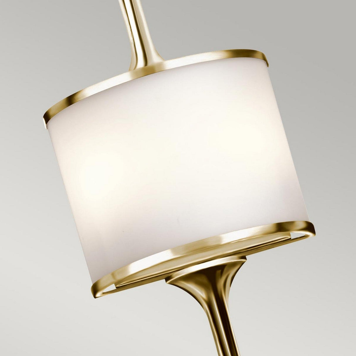 A close-up of the Mona 2 Light Large Wall Light in polished brass, featuring a modern cylindrical shape with a white shade, hanging against a plain gray background. The sleek design seamlessly blends mid-century simplicity with elegance.