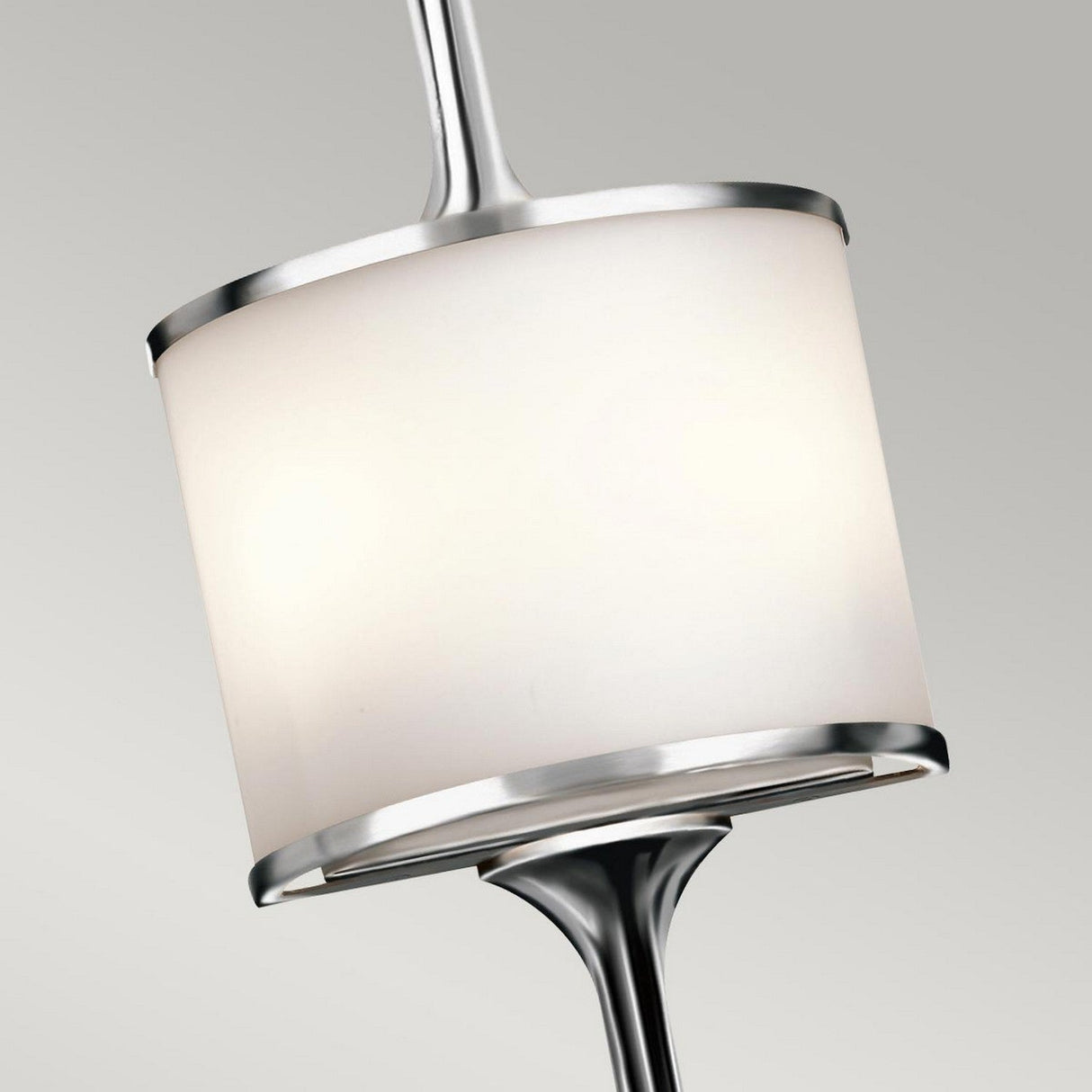 A close-up image of the Mona 2 Light Large Wall Light - Polished Chrome, featuring a modern pendant design with a cylindrical white shade and sleek silver accents, set against a light gray background. The fixture's contemporary aesthetic is highlighted by its smooth lines and shiny finish.