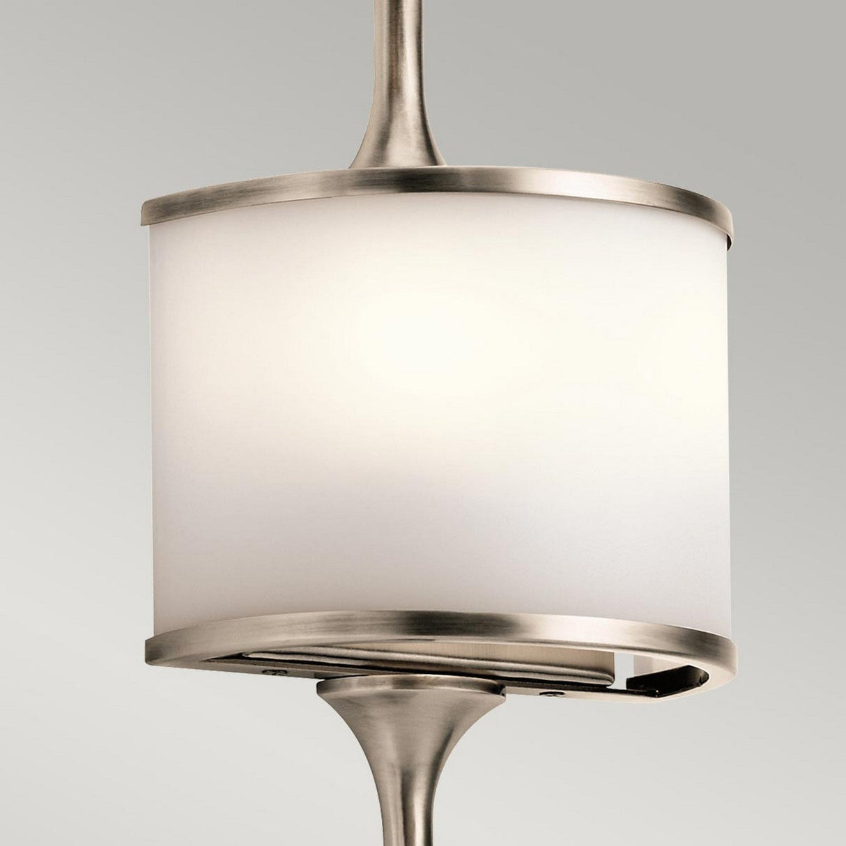 A detailed view of the Mona 2 Light Small Wall Light in a sleek silver finish, showcasing its cylindrical white shade and brushed metal accents. It features an energy-efficient G9 LED lamp and is suspended from the ceiling against a neutral gray background, with the light turned off.