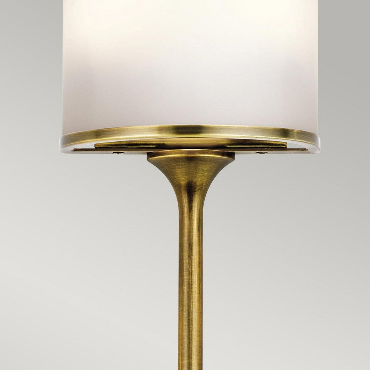 Close-up of the Mona 2 Light Small Wall Light showcasing a mid-century design with a natural brass finish and a cylindrical white shade against a plain gray background.