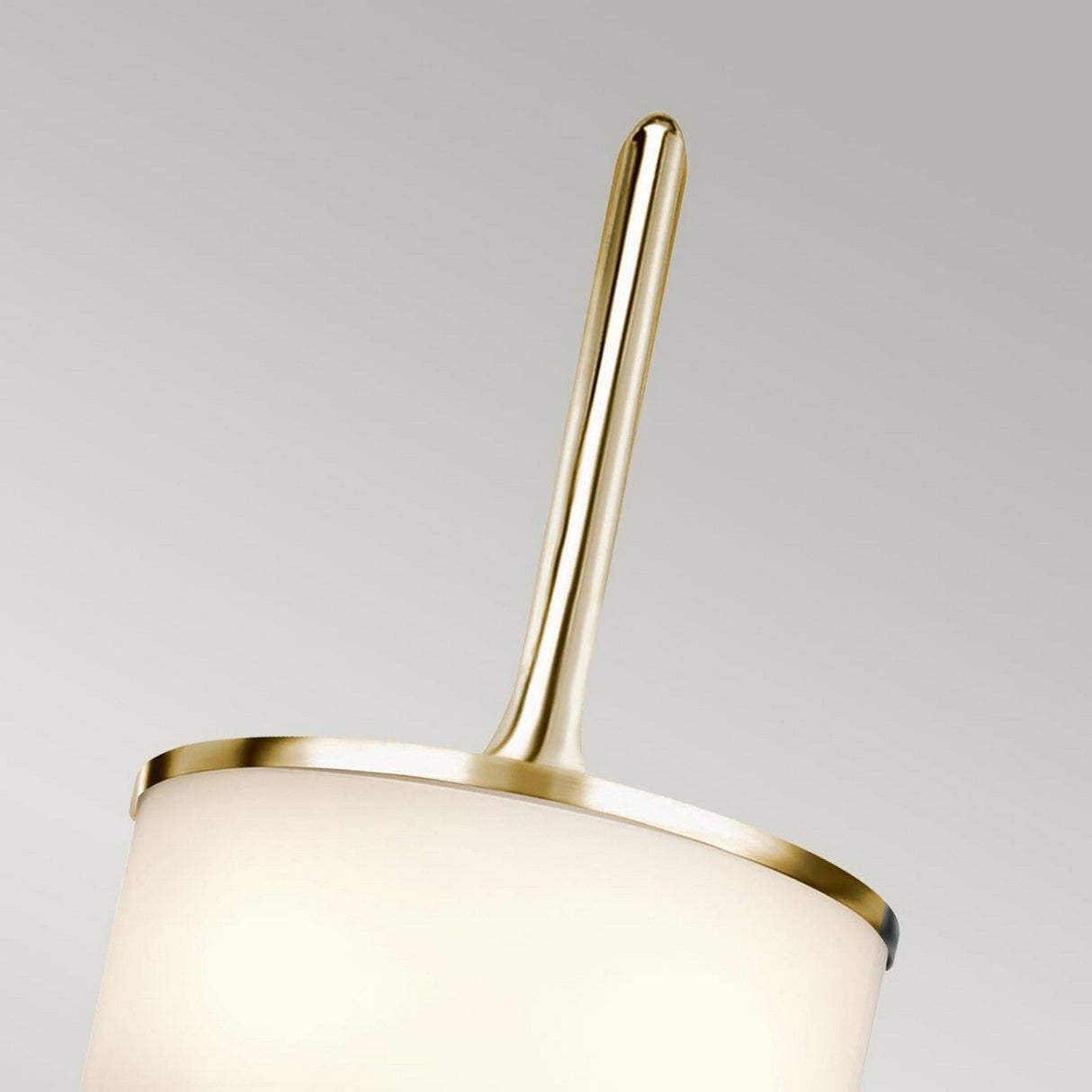 Close-up of the Mona 2 Light Small Wall Light, featuring a cylindrical white shade with gold trim that echoes mid-century style. An elegant polished brass handle extends vertically from the top against a smooth, gradient grey background.