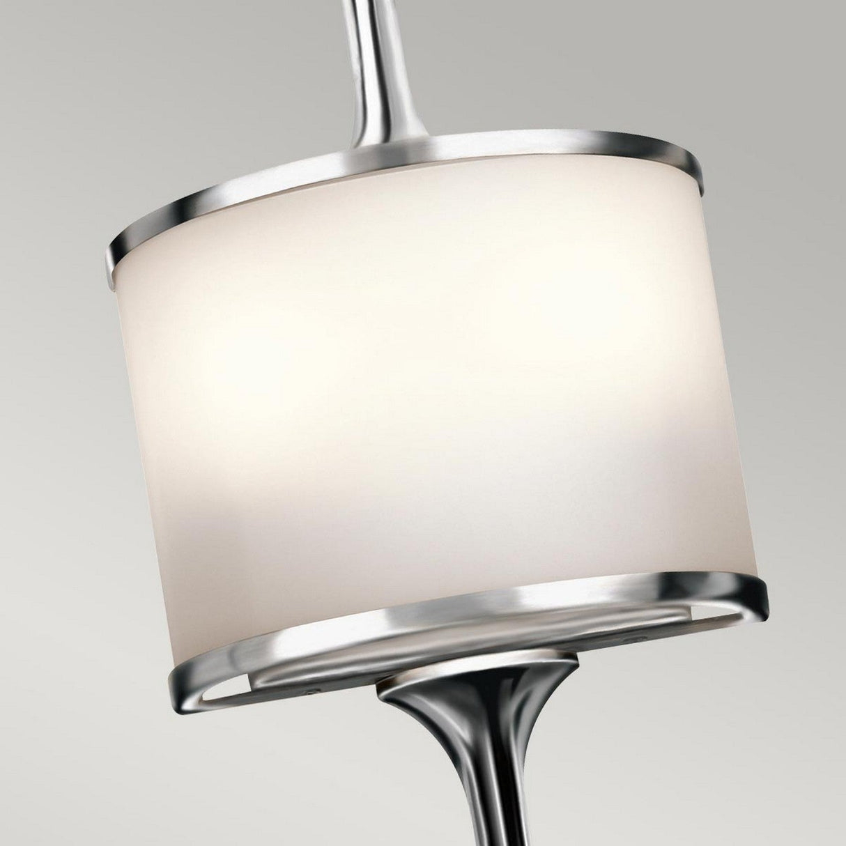 Close-up of the Mona 2 Light Small Wall Light in polished chrome, showcasing a modern design with a cylindrical frosted glass shade and illuminated by G9 LED lamps, set against a plain gray background.