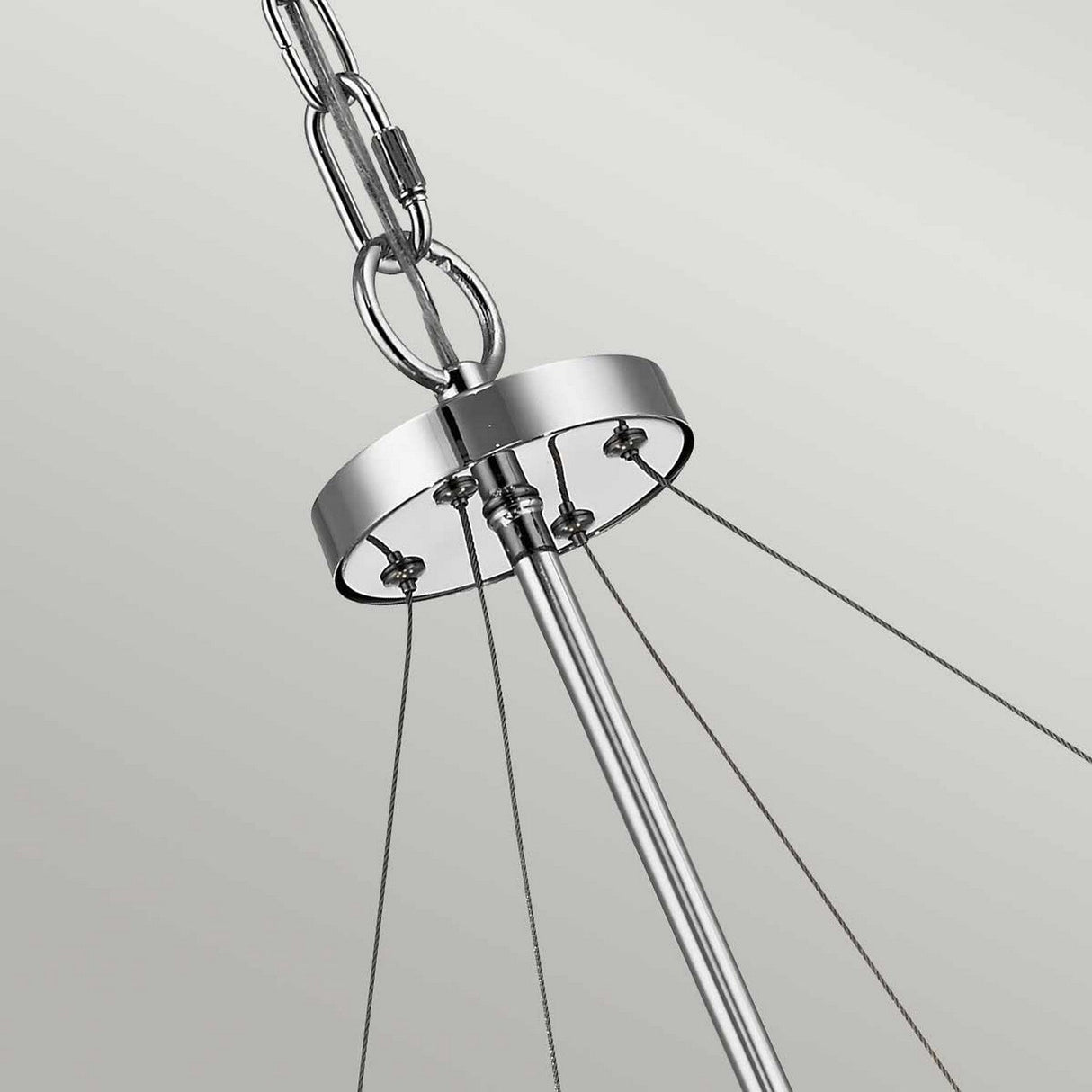 A detailed view of the Piper 6 Light Chandelier - Polished Chrome reveals its sleek finish, featuring a circular metal canopy with several wires radiating outward. The chandelier is adorned with elegant glass bead accents and is suspended by a chain against a simple, light-colored wall.