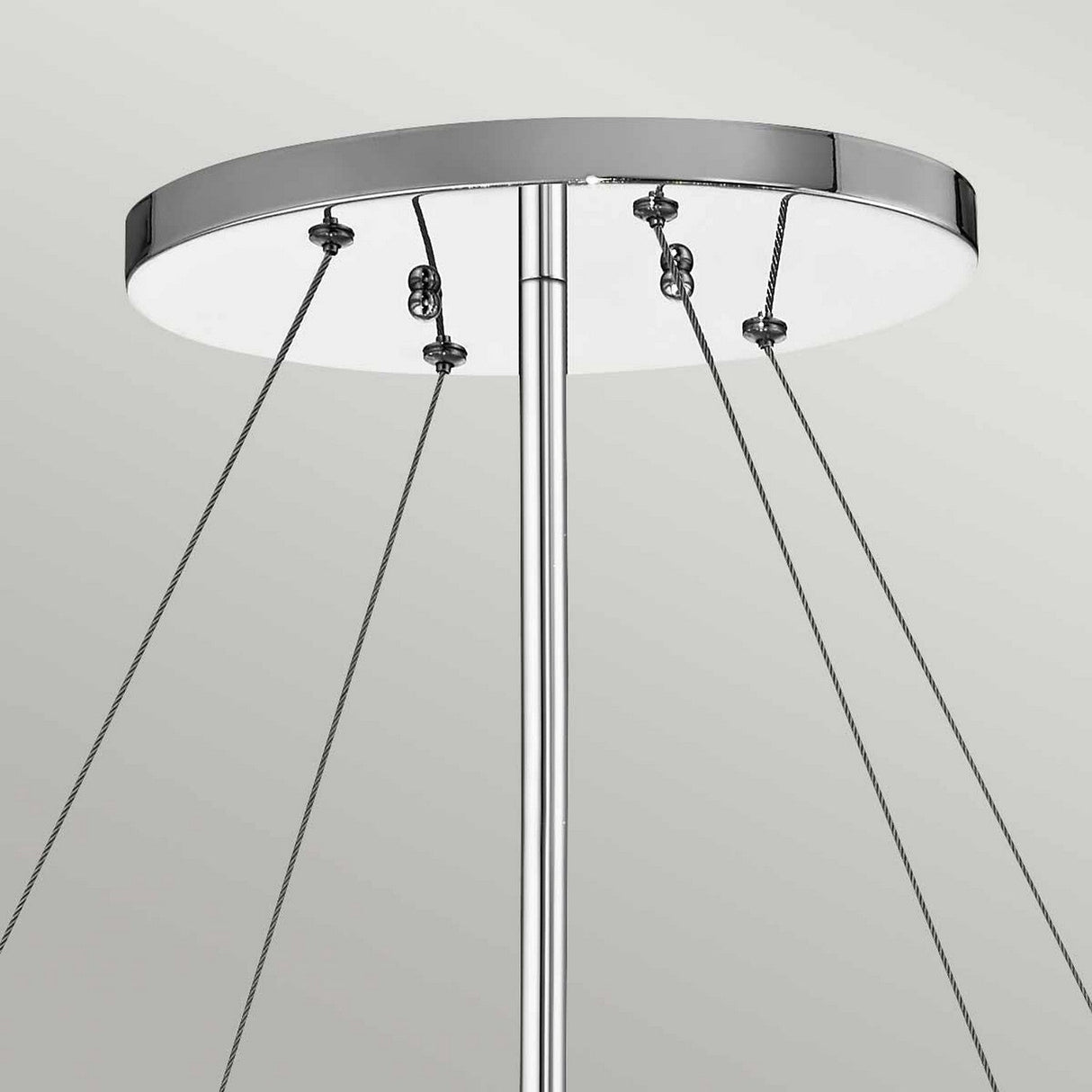 Close-up of the Piper 6 Light Oval Chandelier in polished chrome, featuring a modern ceiling-mounted design with multiple cables extending from its round base and glass bead accents for an elegant touch, set against a light gray background.