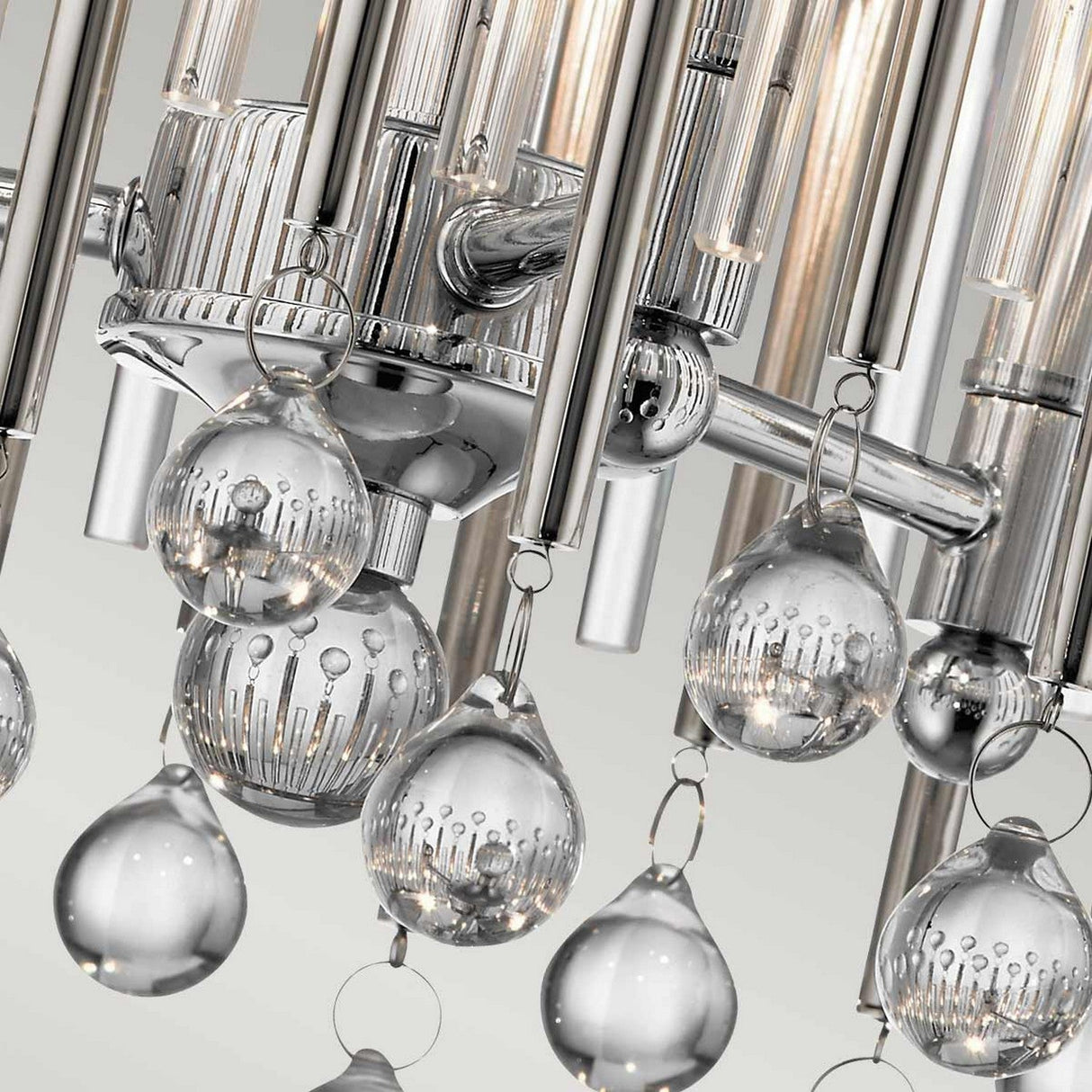 This Piper 3 Light Semi Flush fixture in polished chrome showcases a modern design with metallic rods and hanging glass orbs. The clear, textured orbs brilliantly reflect light, creating vibrant patterns and embodying contemporary elegance effortlessly.