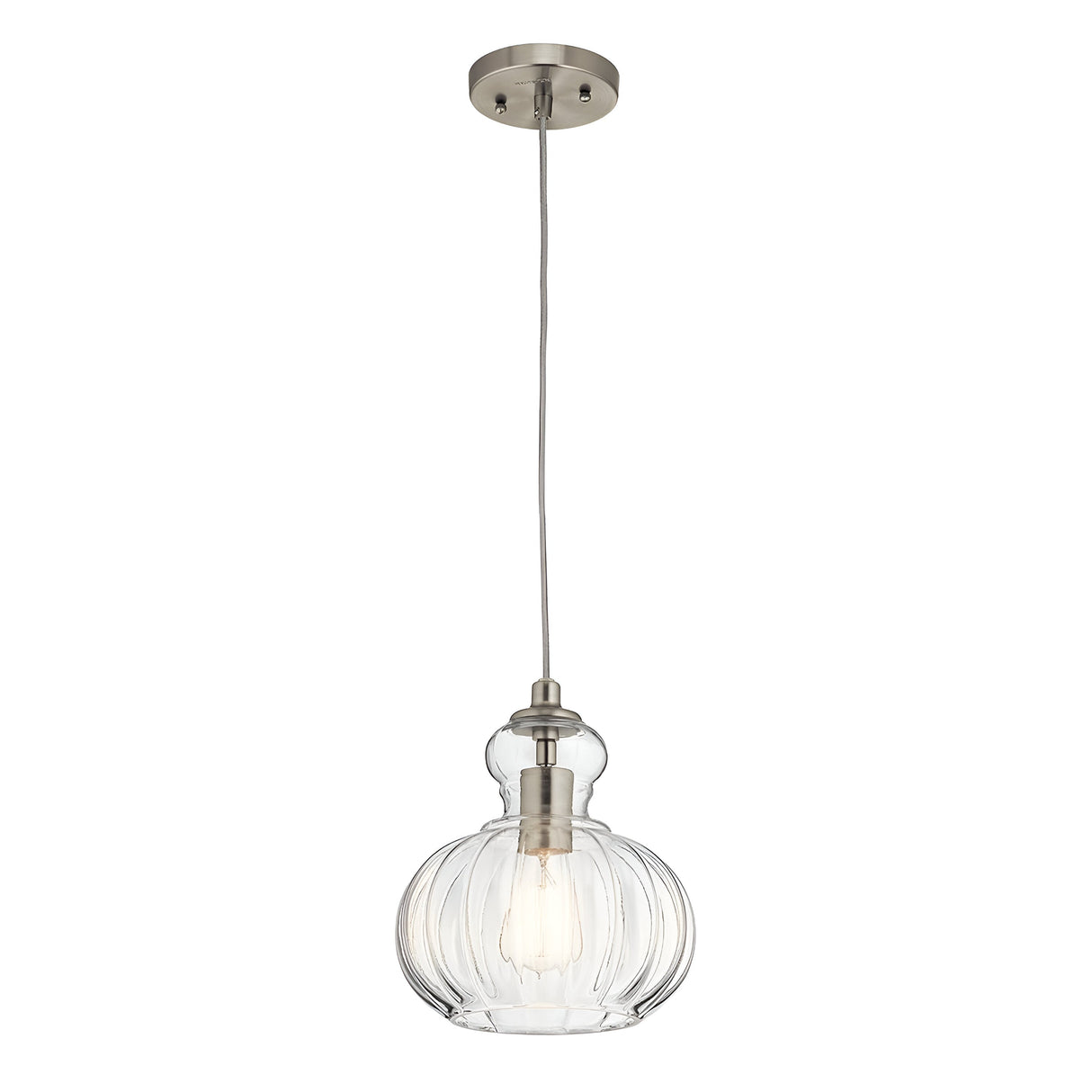 The Riviera-1 1 Light Pendant - Brushed Nickel boasts a transparent, ridged glass shade that showcases the visible bulb, elegantly suspended from a stylish metallic fixture on a cord. Its vintage-inspired design and brushed nickel finish offer an elegant, contemporary aesthetic.