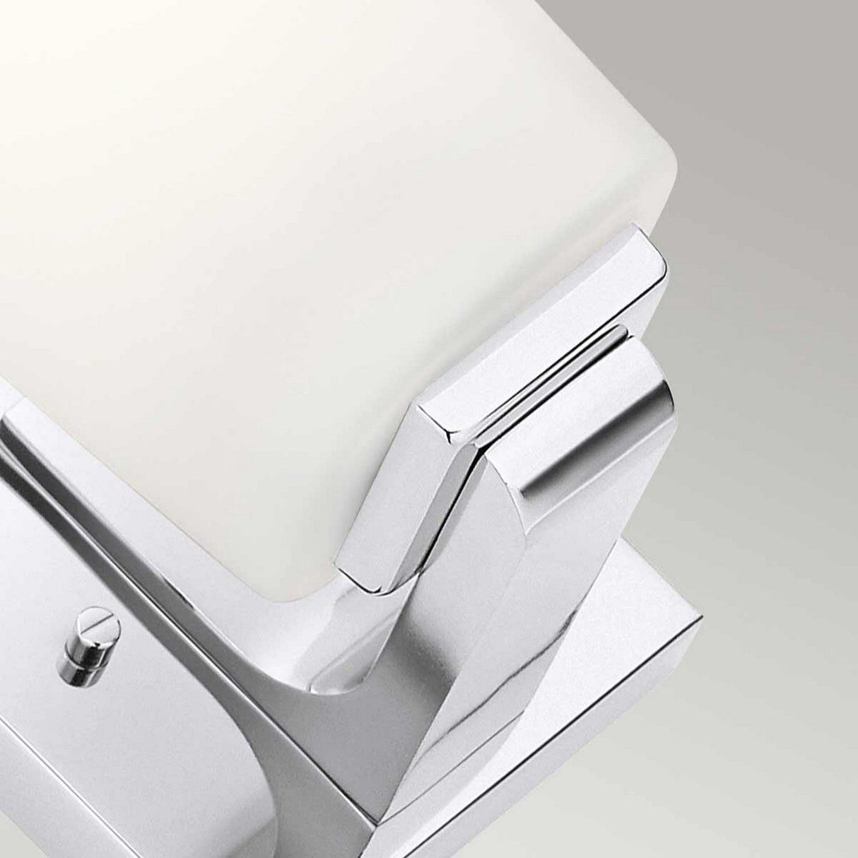 Close-up of a modern, minimalist faucet with a chrome finish against a neutral background. Alongside is the Roehm 1 Light Wall Light in polished chrome, enhancing the space with its sleek design. The faucet features clean lines and a rectangular handle, suggesting a contemporary aesthetic.