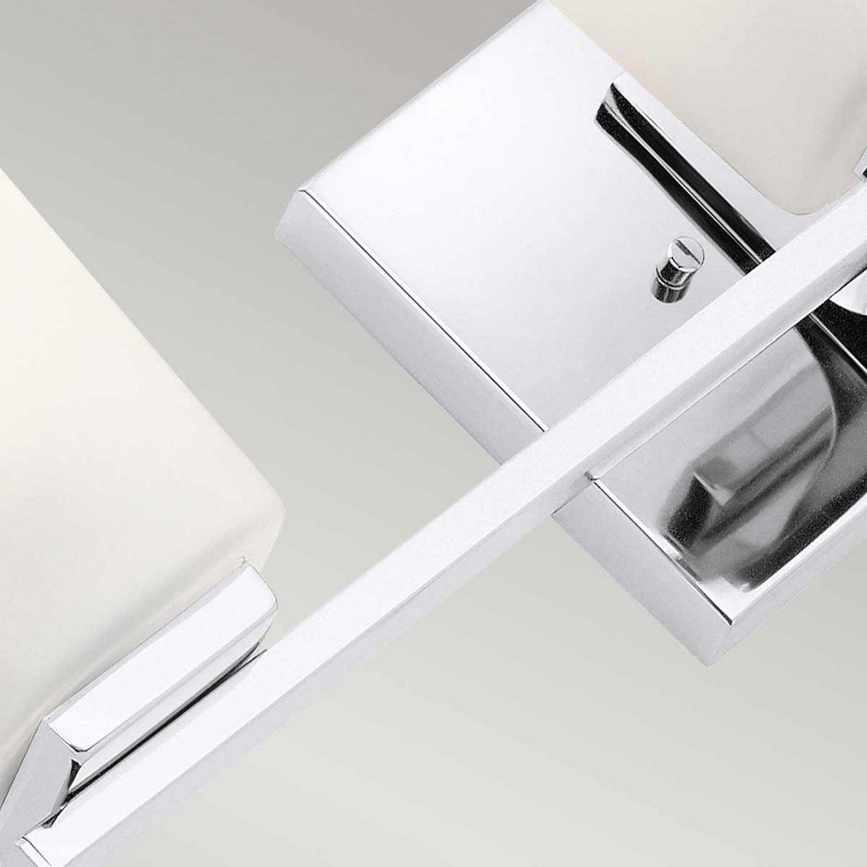 Close-up of the Roehm 3 Light Wall Light - Polished Chrome, featuring two opal glass shades. The sleek design showcases a polished chrome frame and surfaces, providing a contemporary look against a light gray background.