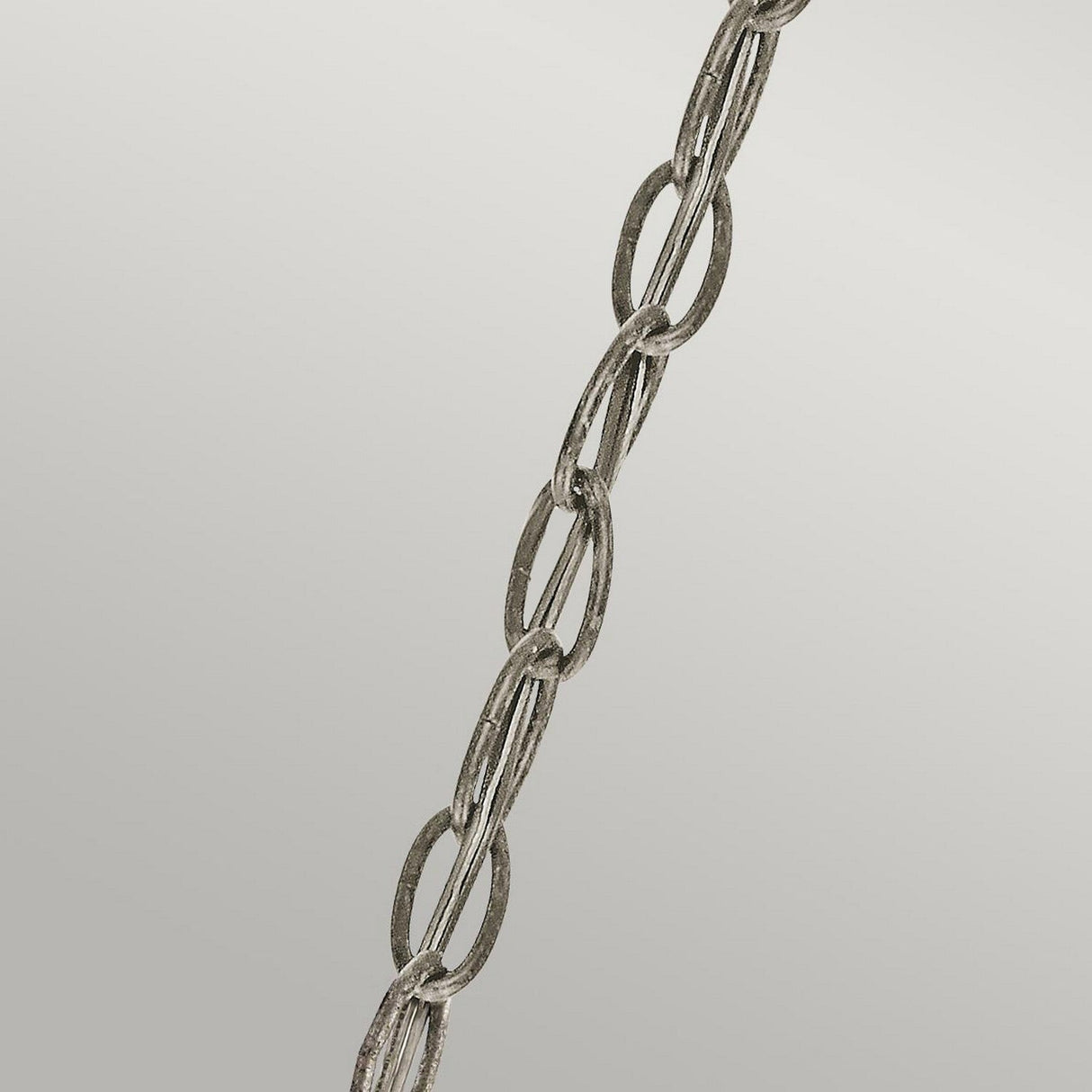 A close-up image of the Rosalie 1 Light Pendant in Sterling Gold, featuring a metal chain suspended diagonally against a plain gray background, evokes the charm of Williamsburg design. The chain consists of interlinked oval-shaped links with a slightly weathered texture, reminiscent of antique mercury glass.