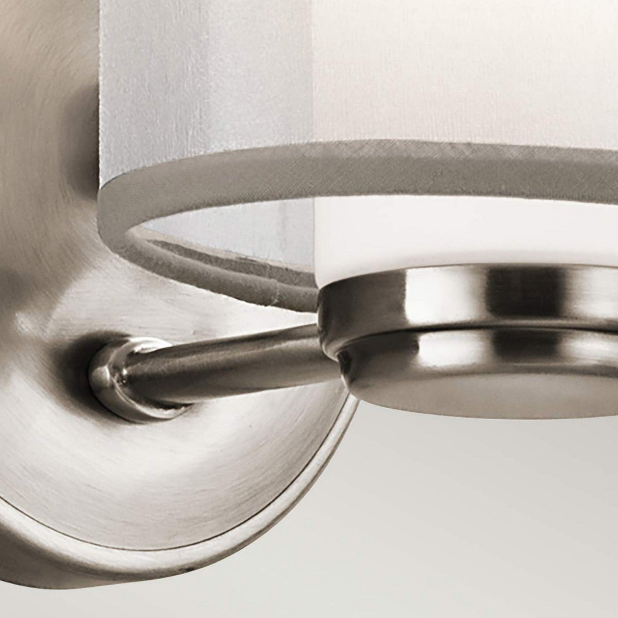 Close-up of the Saldana 1 Light Wall Light - Silver, featuring a sleek silver finish and an opal glass shade, mounted on a light-colored wall. The fixture showcases a minimalist design.