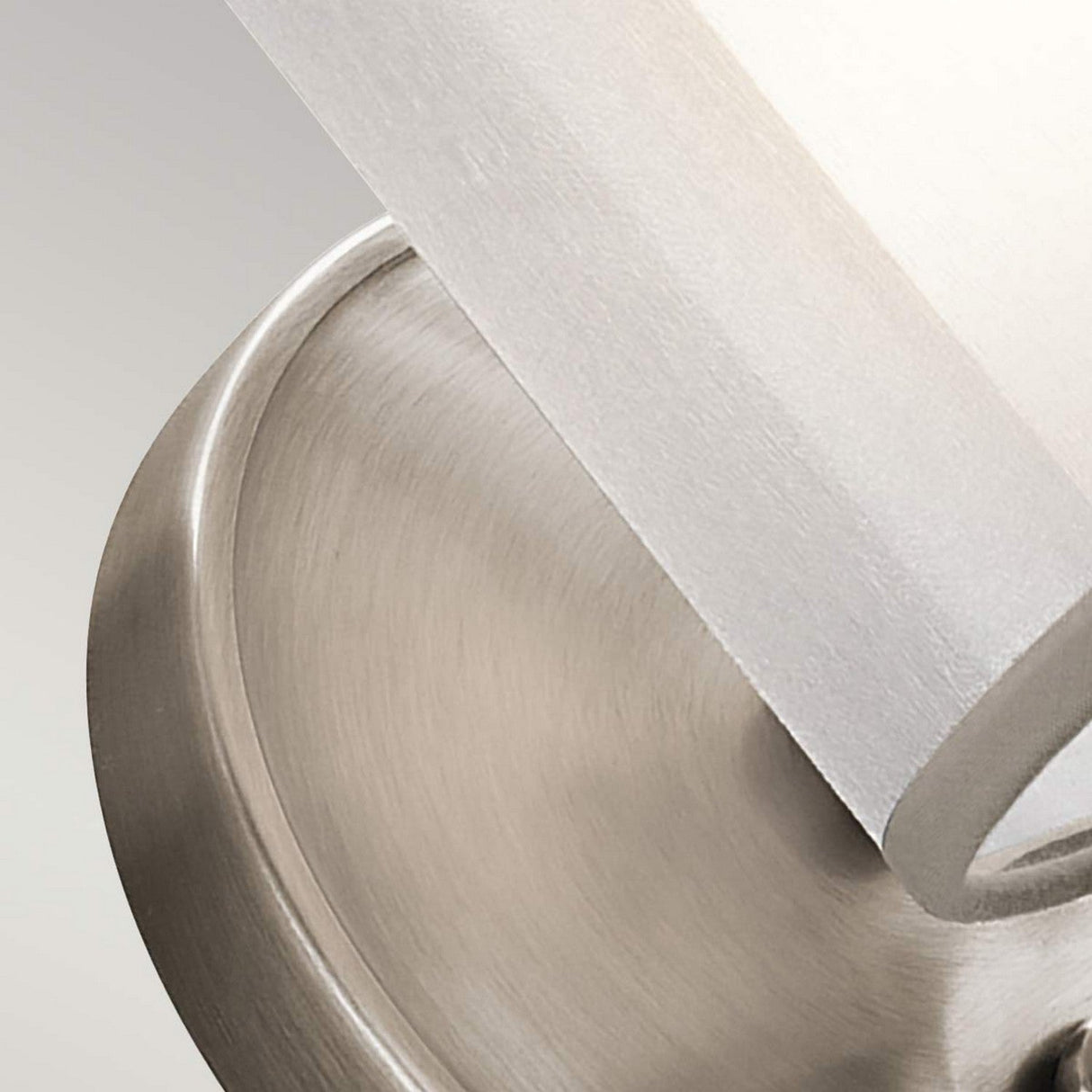 A close-up of the Saldana 1 Light Wall Light showcases its modern appeal, featuring a sleek metal base and an opal glass cover. With clean lines and a sophisticated silver finish, this fixture enhances any space with its elegant aesthetic.