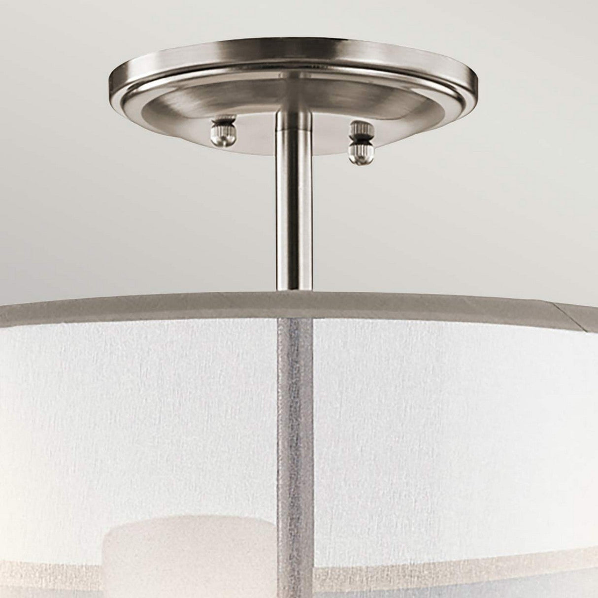A close-up view of the Saldana 3 Light Chandelier - Silver, highlighting its modern ceiling light fixture with a brushed nickel finish. The fixture showcases a cylindrical organza shade and a metallic base attached to the ceiling.