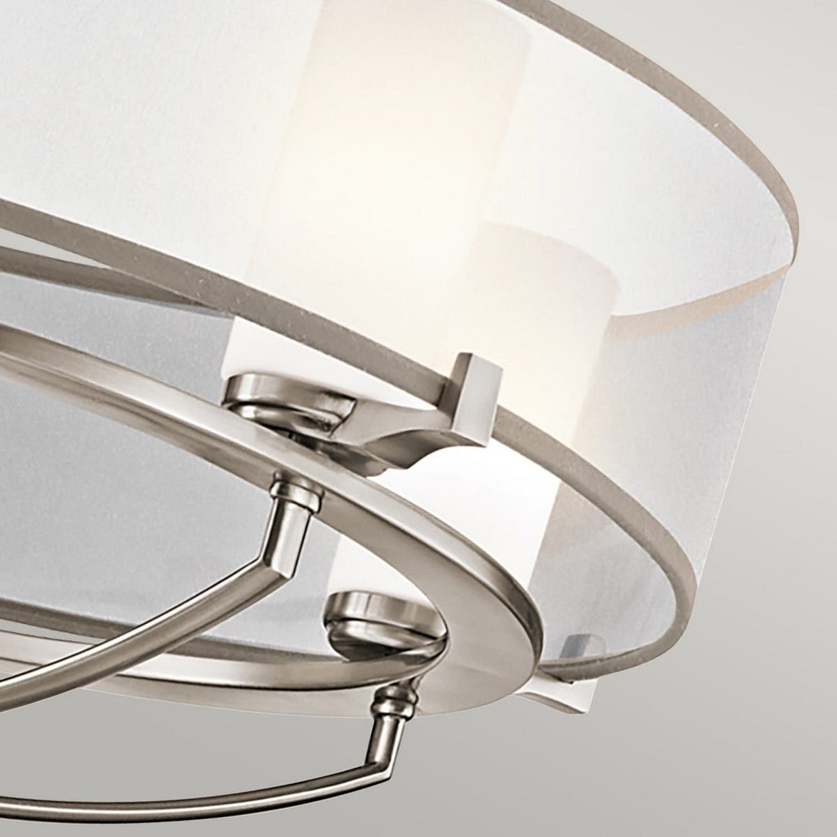 Close-up of the Saldana 5 Light Chandelier in silver, showcasing its circular metal frame with a matte finish and an organza shade. The soft lighting from the chandelier creates a warm ambiance against a neutral background.