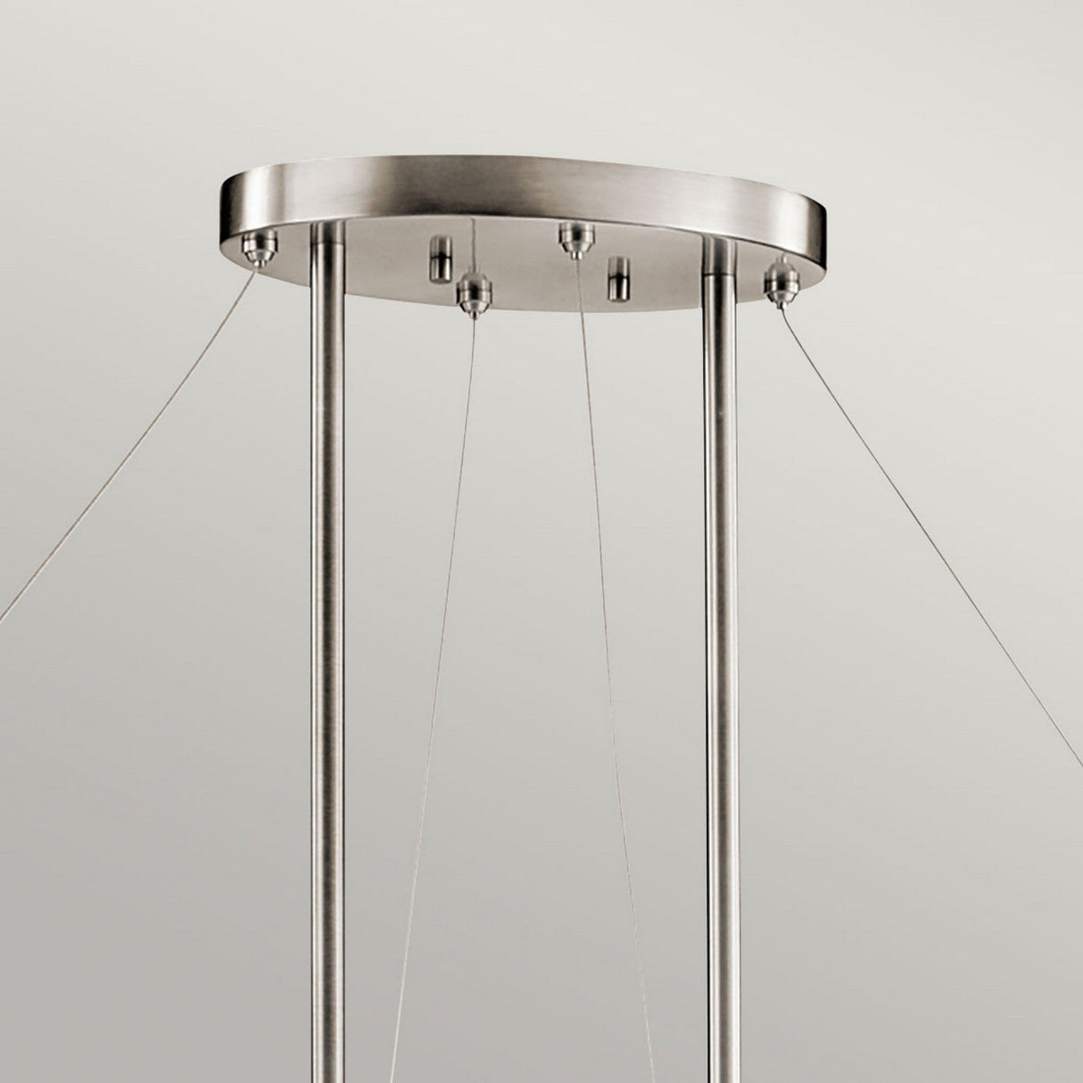 The Silver Coral 4 Light Oval Island Suspension - Silver is a brushed metal fixture showcasing a contemporary design. It features an oval ceiling mount with three vertical rods, suspended by four slender wires, and its textured metal frame enhances the minimalist style against a neutral backdrop.