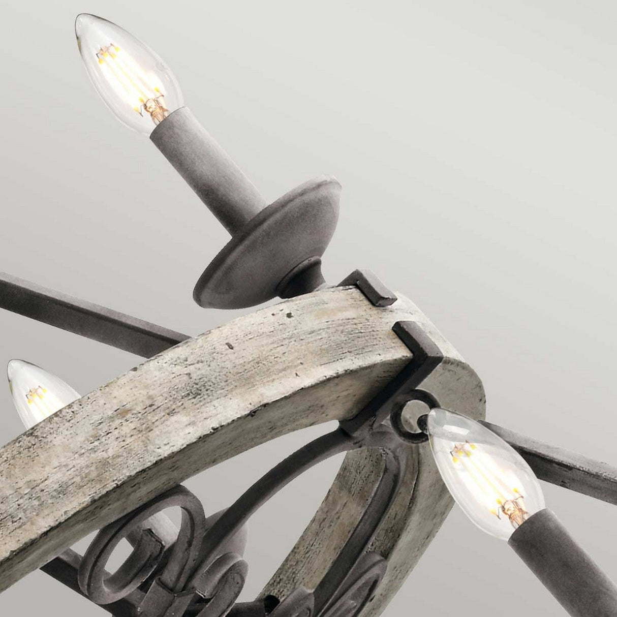 Close-up view of the Taulbee 15 Light Chandelier - Weathered Zinc, featuring exposed vintage-style light bulbs. The metal frame, with its weathered zinc finish, adds an industrial touch to the design. The pointed bulbs are evenly spaced around the fixture, enhancing its rustic aesthetics.