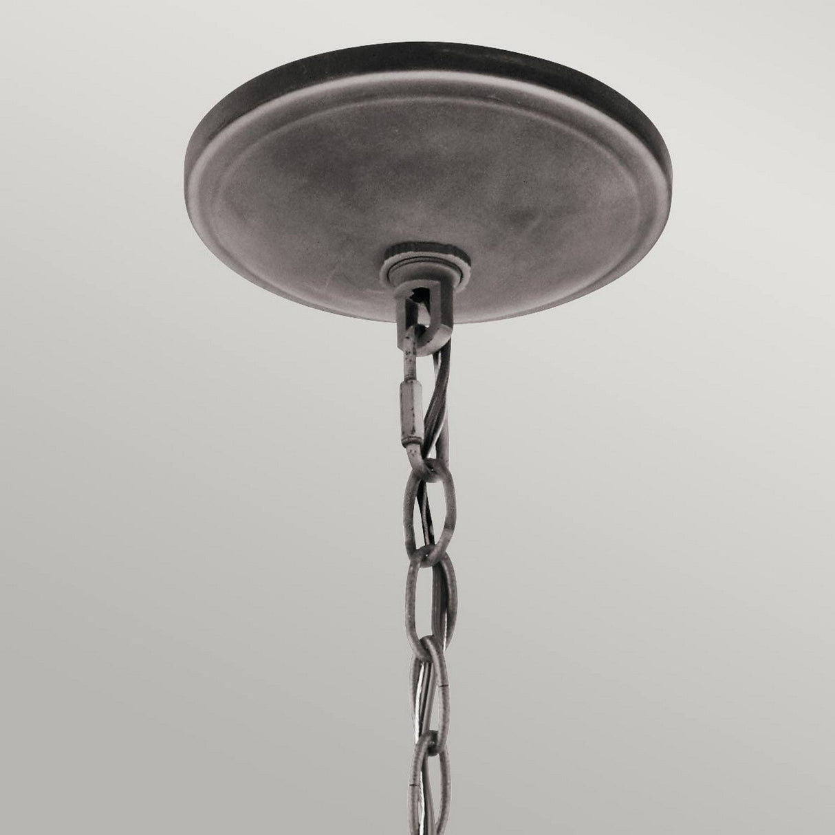 The Taulbee 6 Light Chandelier, featuring a round metallic ceiling canopy with a linked chain, exudes a lodge-inspired design. The soft gray background beautifully contrasts with the chandelier's weathered zinc finish.