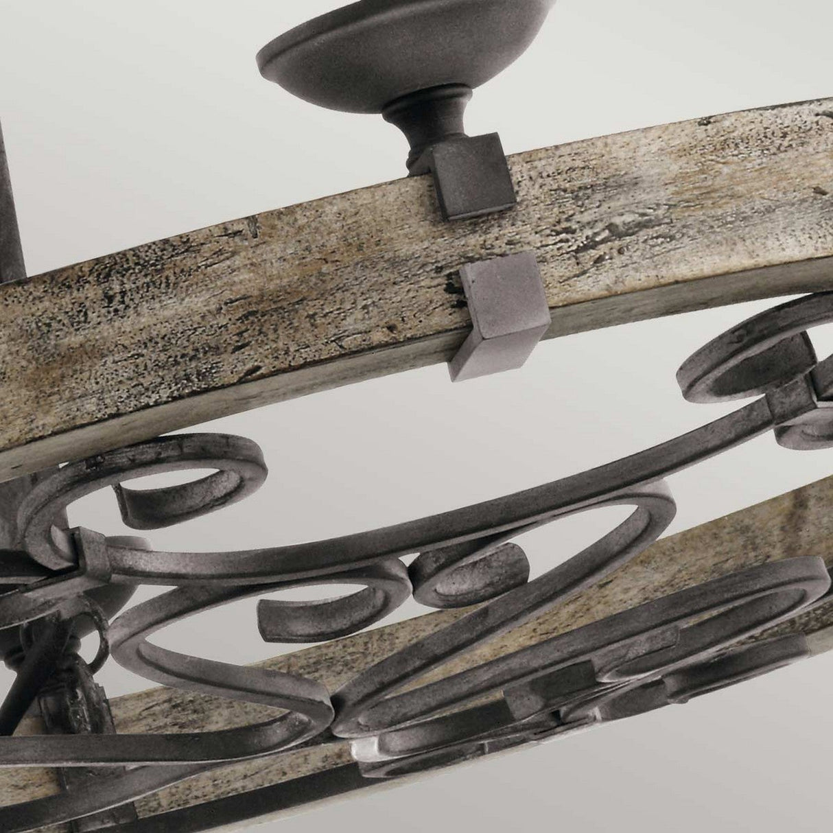 A close-up of the Taulbee 6 Light Chandelier in rustic wood and weathered zinc highlights its intricate scrollwork and metal detailing against a neutral background, providing it with an elegant, vintage appearance.