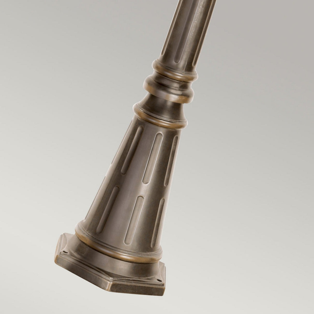 A close-up of the Tournai 3 Light Extra Large Lamp Post in bronze highlights its vintage charm, featuring decorative vertical grooves and a stacked design. This elegant outdoor fixture stands gracefully against a neutral gray background.