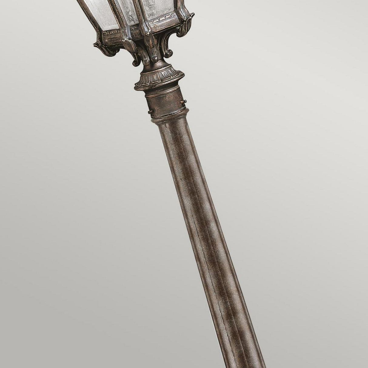 Close-up of the Tournai 1 Light Medium Pillar in bronze, tilted diagonally against a plain gray background. This ornate, antique-style street lamp post is crafted from hand-cast aluminum and showcases intricate detailing with a beautifully weathered finish.