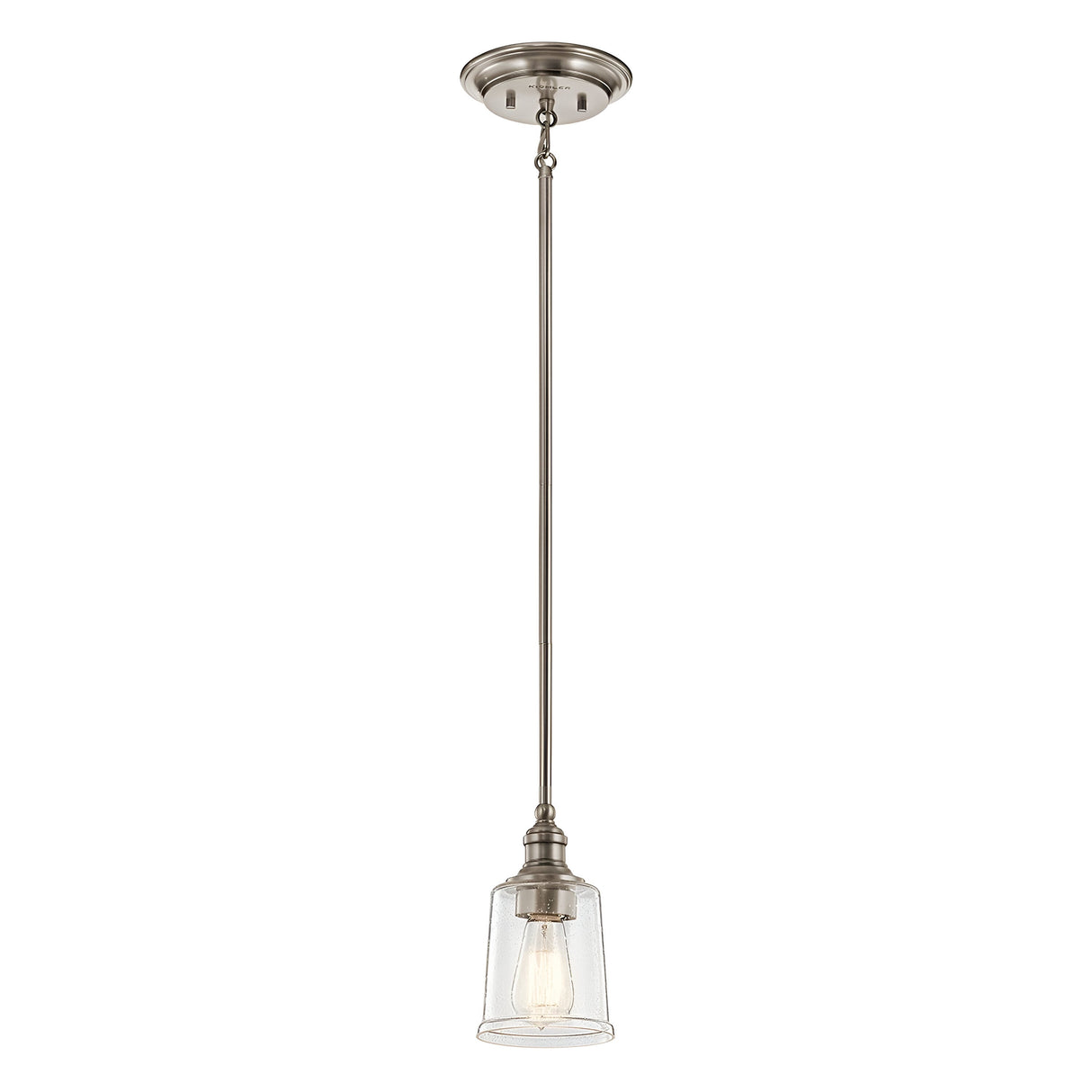 The Waverly 1 Light Mini Pendant - Silver is a vintage-style mini pendant light fixture, showcasing a brushed nickel silver finish and a clear glass shade with a visible bulb, elegantly suspended from the ceiling by a slender rod.