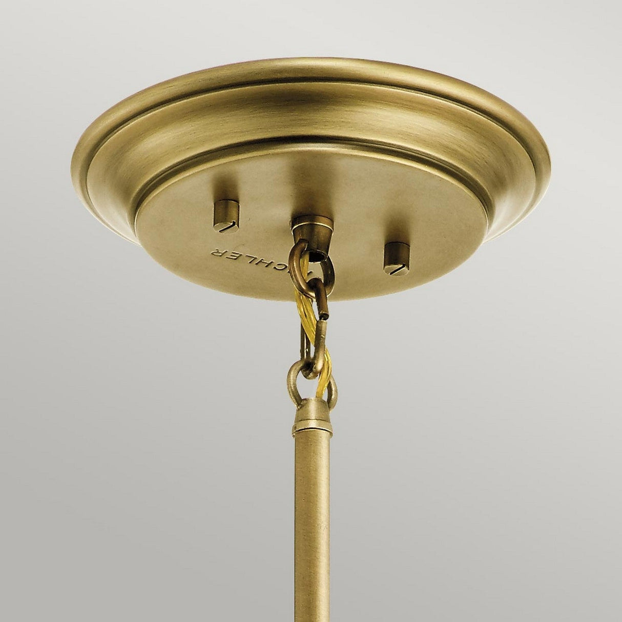 Close-up of the Waverly 1 Light Mini Pendant in Natural Brass attached to the ceiling, showcasing its circular base with hooks and a chain. This mini pendant adds a sleek, metallic touch against a plain background.