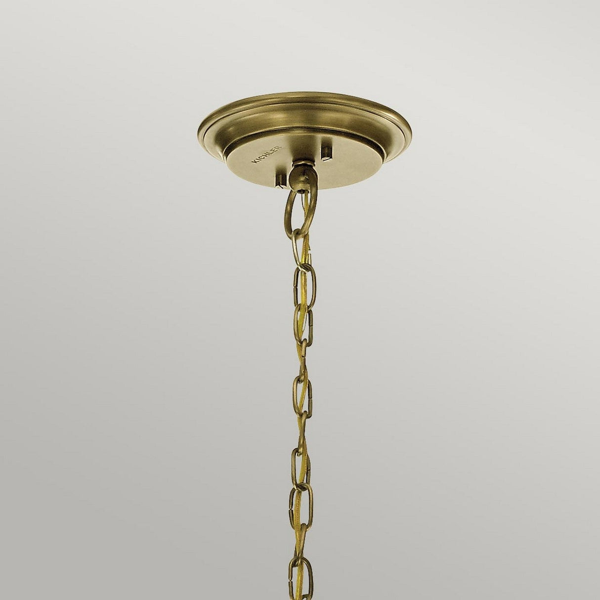 The Waverly 3 Light Chandelier in natural brass features an ornate chain and exudes vintage elegance against a light gray background, showcased in a close-up of its ceiling mount.