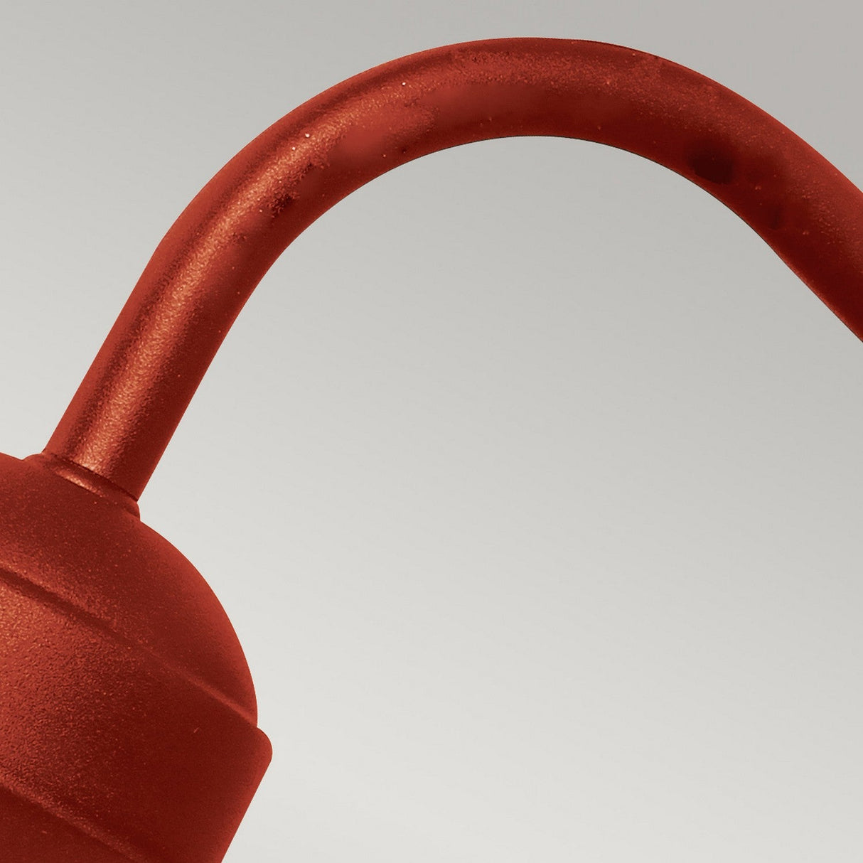 A close-up of the Klampenborg 1 Light Outdoor Wall Light in Oxide Red showcases its smooth curves and subtle texture, set against a plain, light gray background that adds a touch of Scandinavian style.