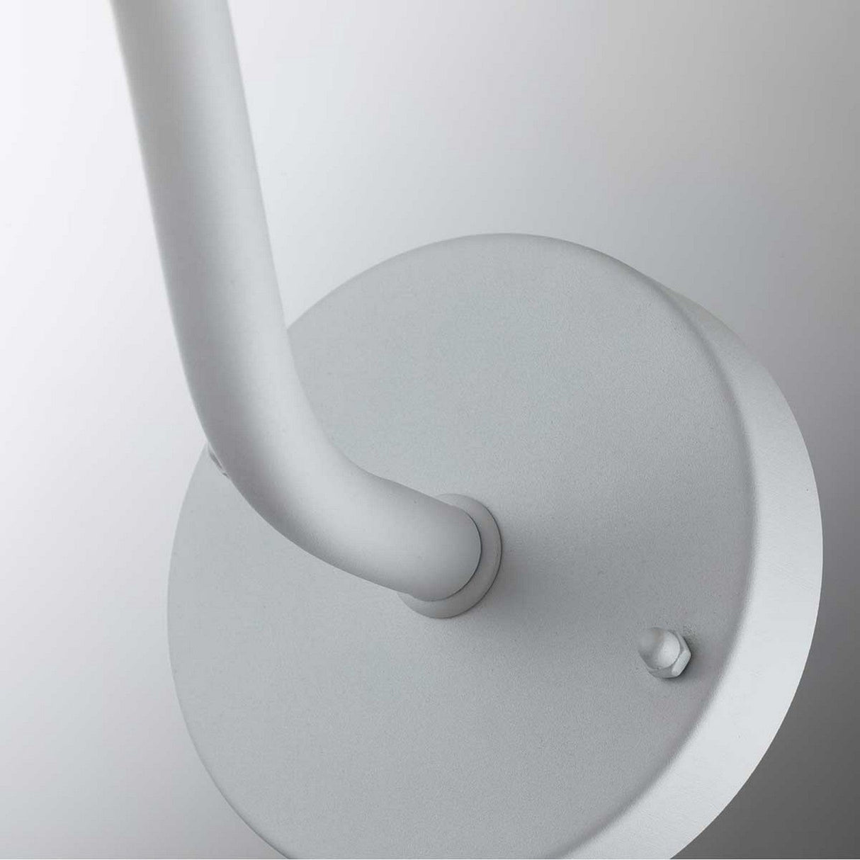 Close-up of the Klampenborg 1 Light Outdoor Wall Light, featuring a minimalistic design with a modern curved metal arm made from durable stainless steel, extending from a round base against a light background.