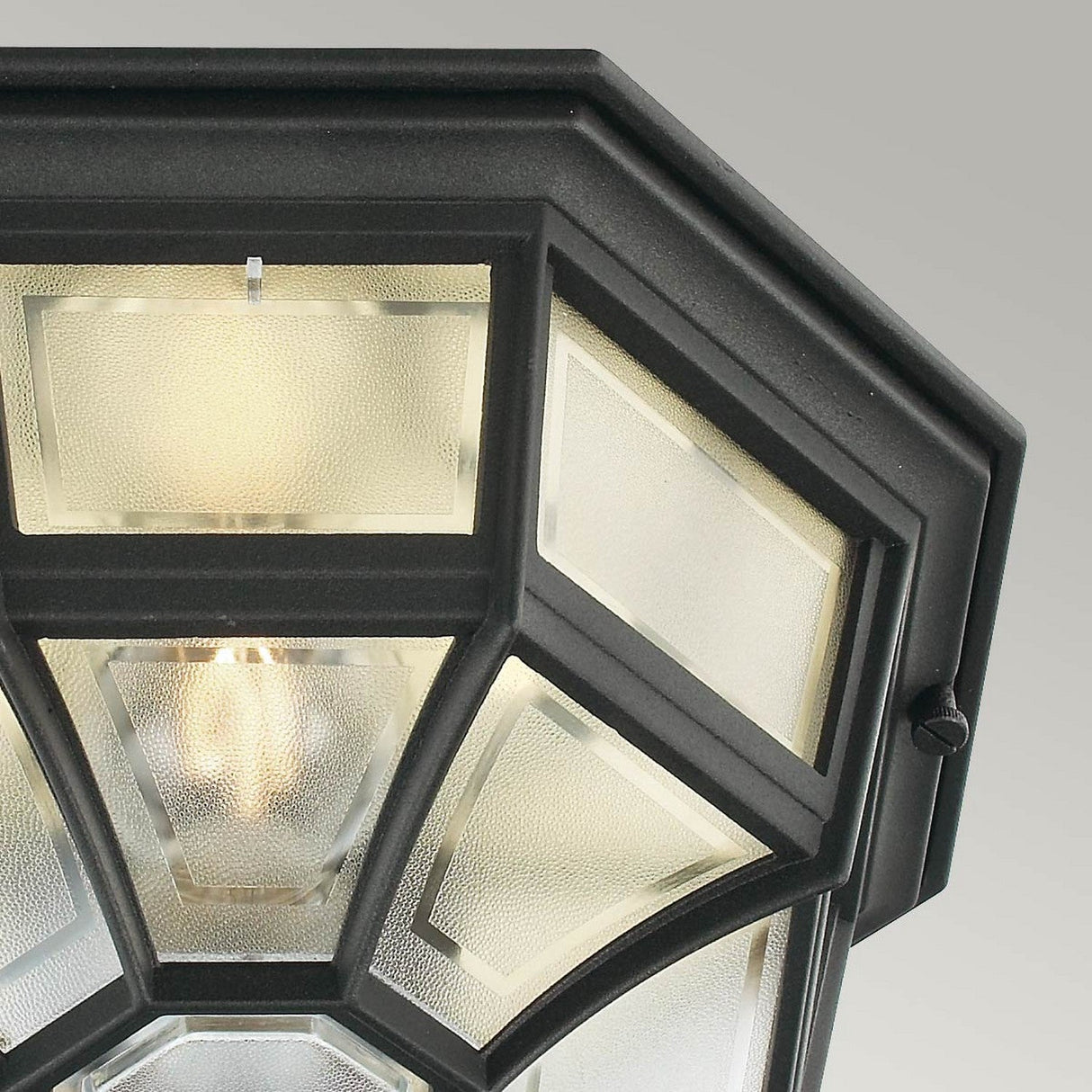 Close-up view of the Latina Outdoor 1 Light Ceiling Light in black, featuring octagonal frosted glass panels with an IP44 rating. The bulb is visible through the textured glass, emitting a soft glow. A black powder coating enhances durability, as shown from below against a neutral background.