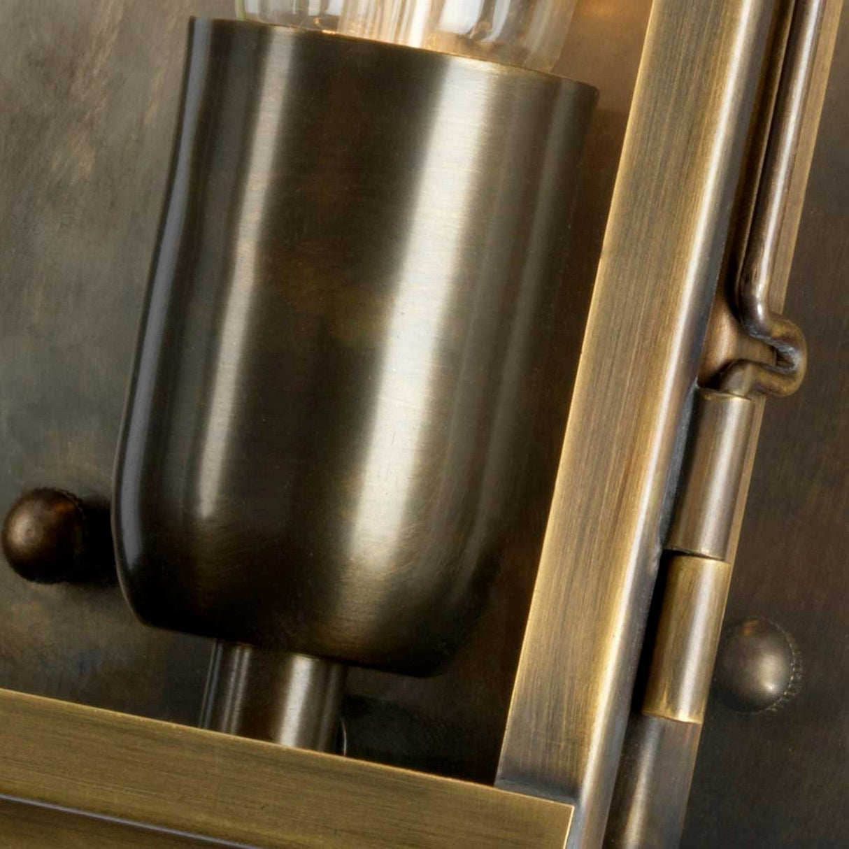 A detailed view of the Lambeth Palace 1 Light Outdoor Wall Light in aged brass showcases its intricate metalwork and well-crafted hinge. The antique patina enhances its vintage charm, beautifully displayed through the clear glass bulb.