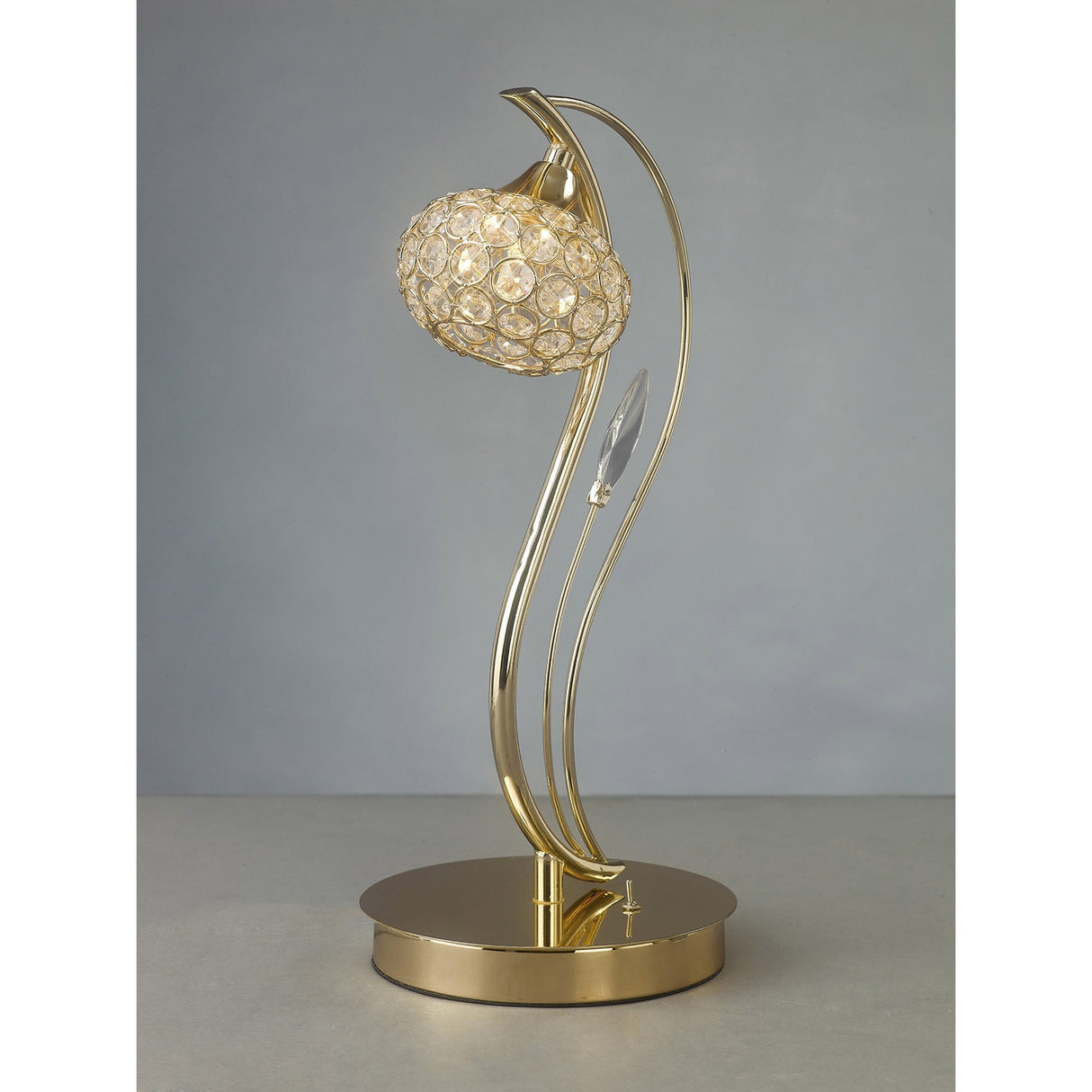 The Leimo 1 Light Crystal Table Lamp in French Gold features a curved stem, crystal-embellished round shade, and shiny circular base, adding modern elegance against a plain gray background.