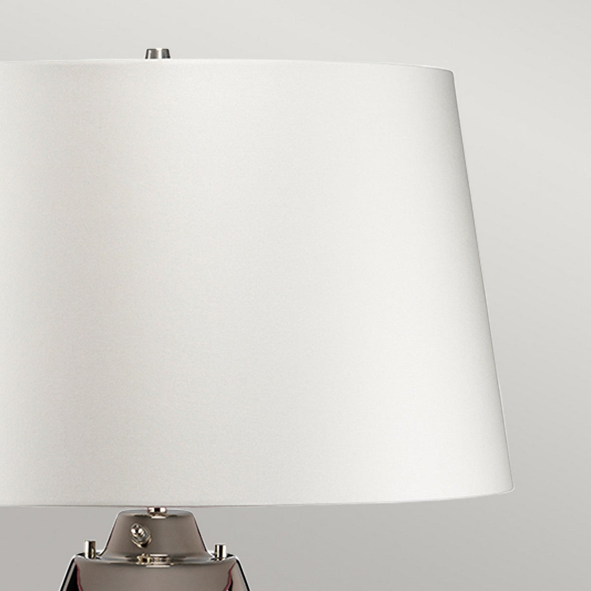 The Lena 2 Light Large Plum Table Lamp with an off-white shade and metallic base is set against a neutral gray background, showcasing its sleek, minimalist design. The use of mouth-blown glass enhances its modern aesthetic, even when the lamp is turned off.