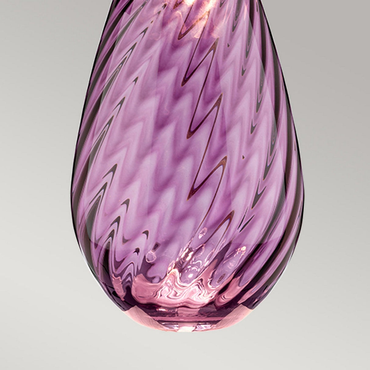 Close-up of a pink glass object with a swirling ripple pattern and a teardrop shape, reminiscent of the Lena 2 Light Large Plum Table Lamp with an Off-White Shade, set against a light gray background.