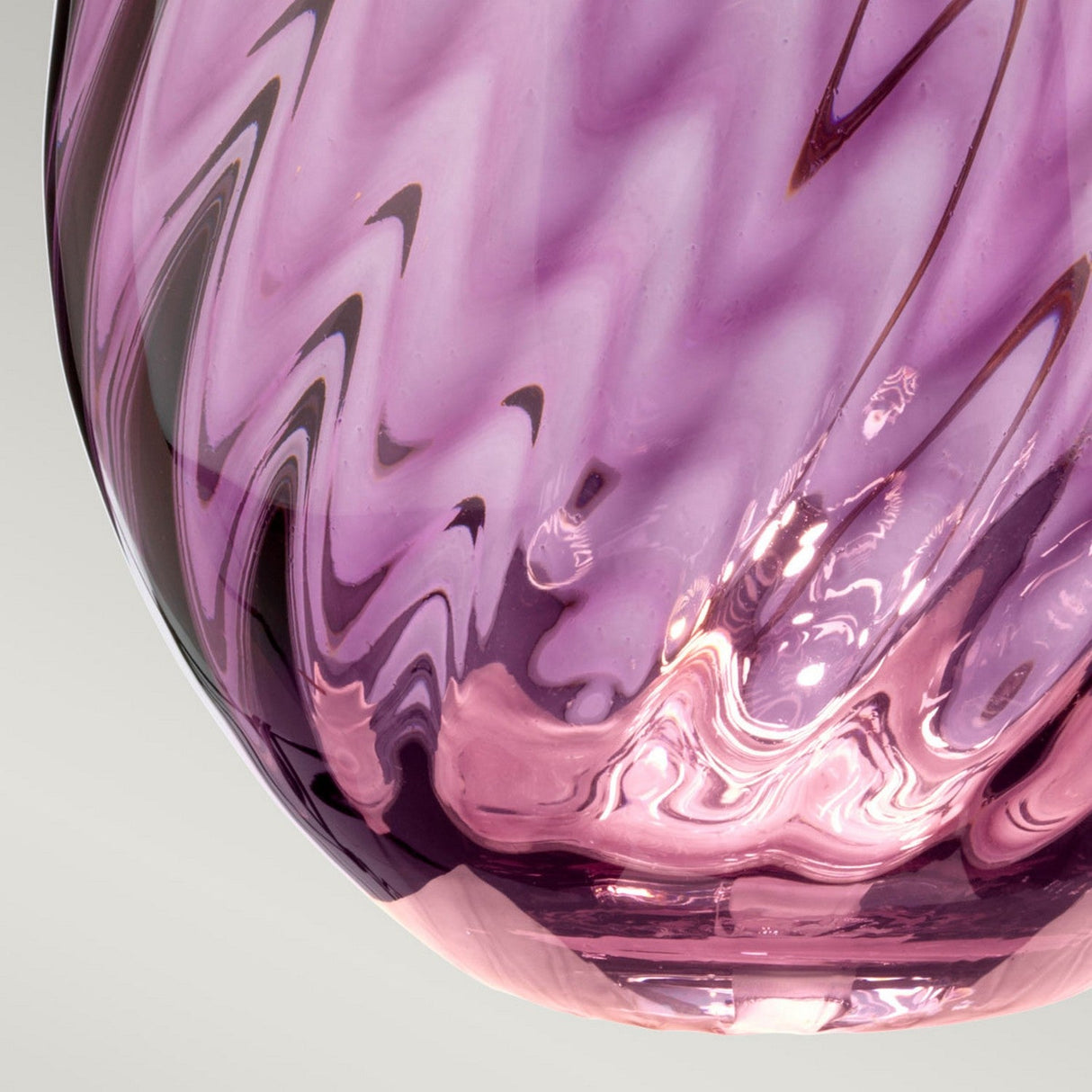 Close-up of the Lena 2 Light Large Plum Table Lamp with a Heather Shade, showcasing its swirling design that creates a captivating play of light and shadow. The plain background accentuates the lamp's intricate textures and glossy finish.