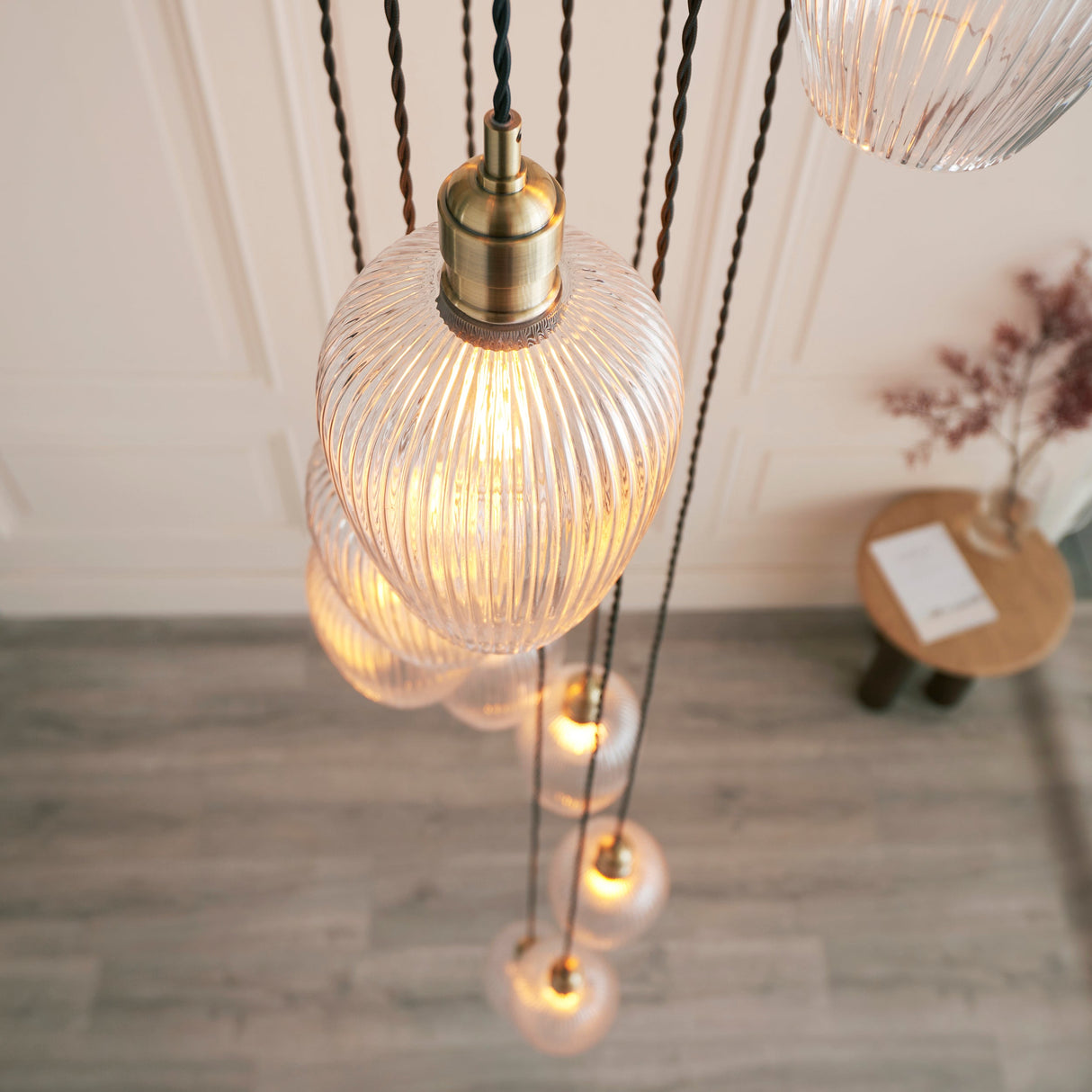Fennhollow Ribbed Cascade 13 light pendant by Lighting No.1, ribbed clear glass globes on twisted flex from an antique brass plate in a tall hall.
