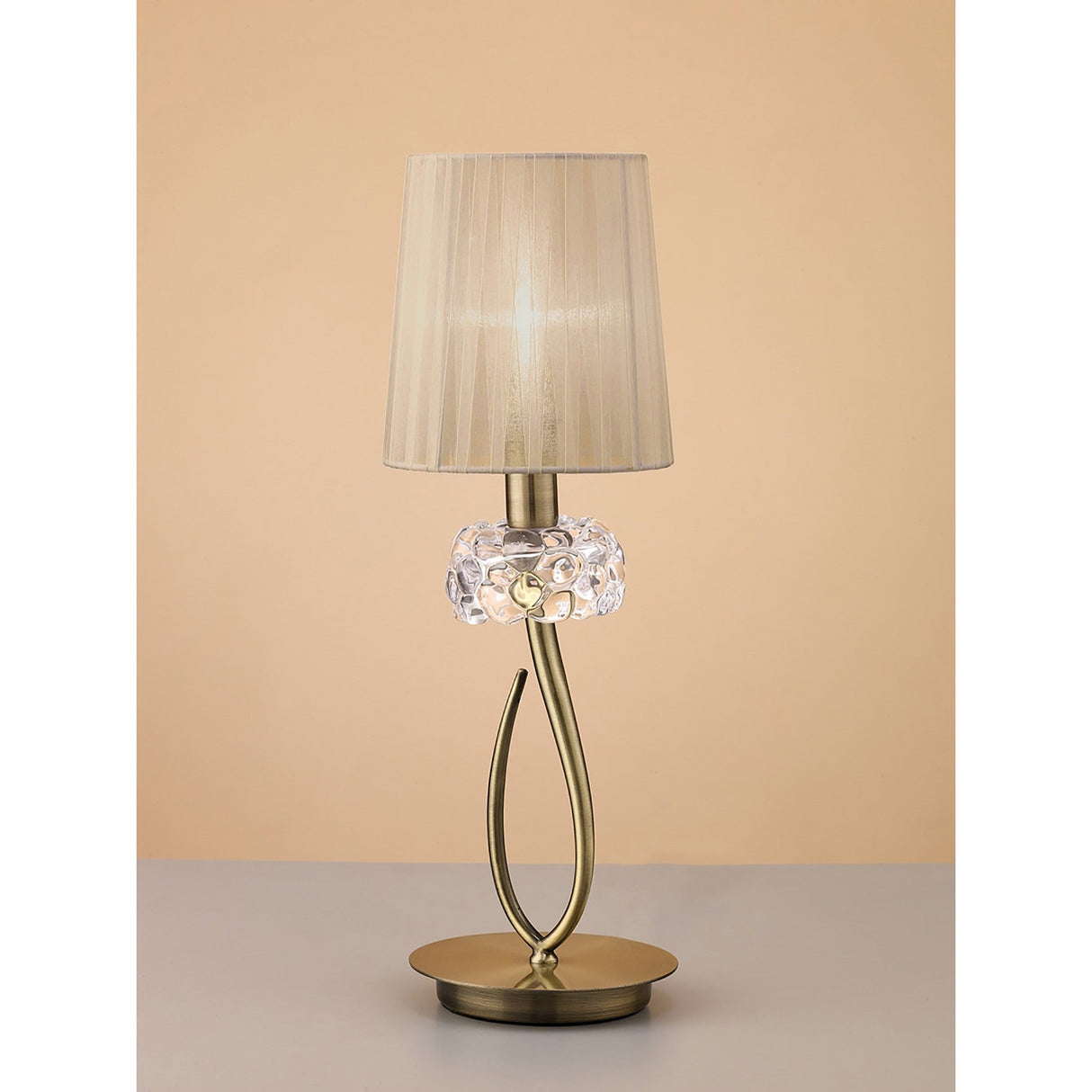 The Loewe Small 1 Light Table Lamp features an antique brass base with a bronze shade, offering stylish ambient lighting that complements neutral beige backgrounds.