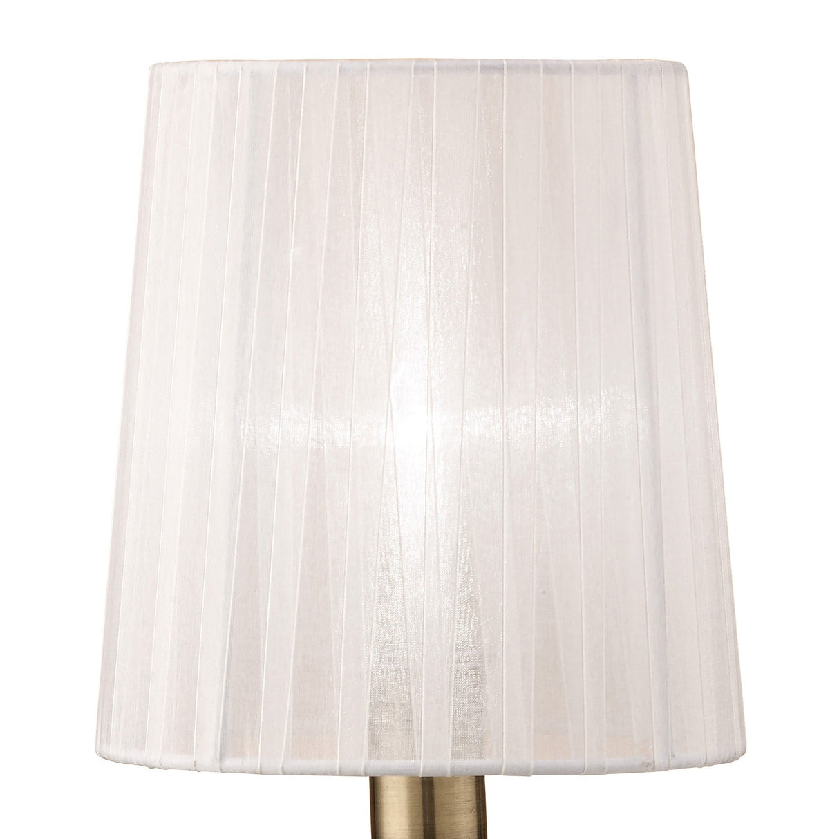 The Loewe Small 1 Light Table Lamp features an antique brass base and a white pleated shade. When lit, it softly illuminates any space, creating a warm and inviting atmosphere.