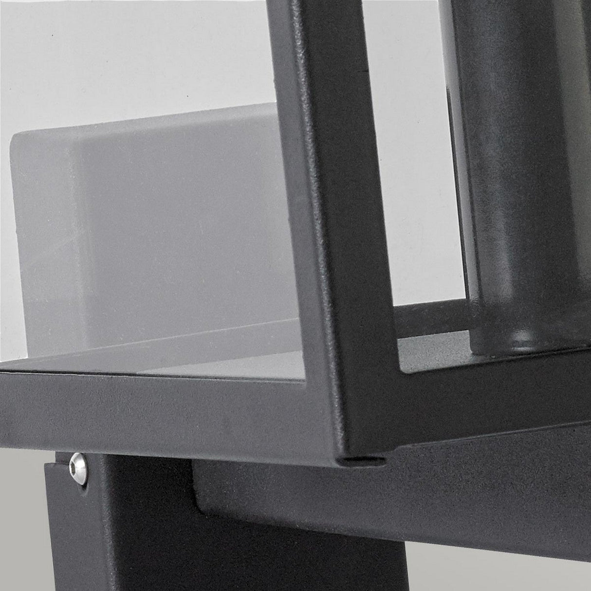 A close-up of the Lofoten Outdoor 1 Light Wall Light in black displays a modern, minimalist design with a sleek metal frame and transparent glass panel. The IP44 rated design boasts clean lines and a geometric style, highlighting its contemporary aesthetic suited for any exterior decor.