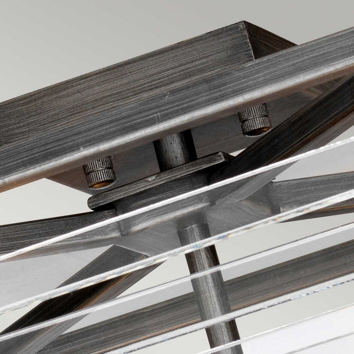 Close-up view of the Louvre 4 Light Flush ceiling fan mount, featuring a graphite finish and multiple blades. The flush fitting mechanism is visible, highlighting the textured hardware and sleek design against a soft background.