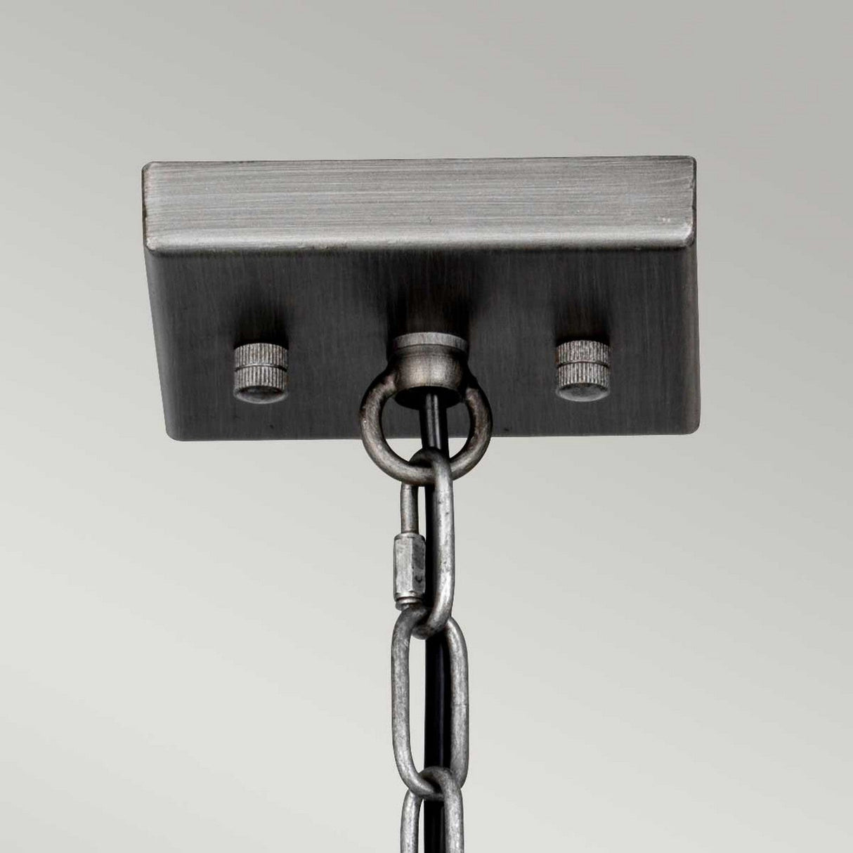 The image highlights a metal ceiling mount complete with an attached chain, featuring a rectangular metal plate accented by two screw heads on either side of the chain connection. Its modern industrial design is accentuated by a sleek graphite finish, making it ideal for suspending the Louvre 4 Light Chandelier - Graphite against a plain backdrop.