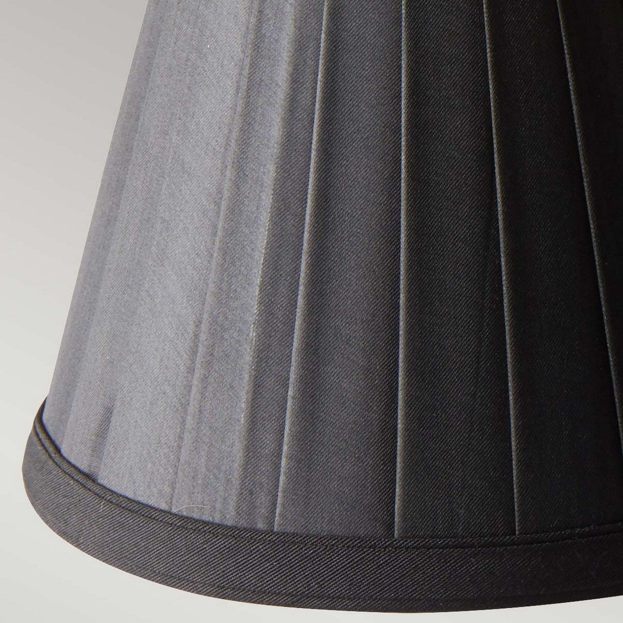 Close-up of the Clip Shades Pleated Black Candle Shade featuring intricate stitching that enhances candle bulb lighting fixtures, highlighting its rich texture against a light gray backdrop.