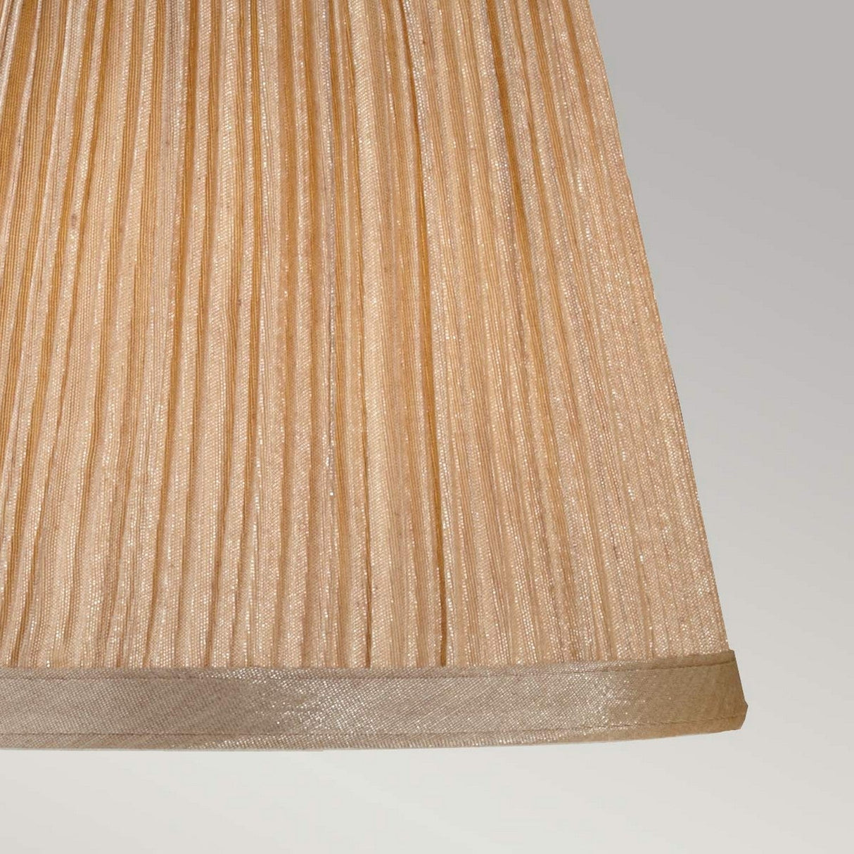 Close-up of the Clip Shades Mushroom Pleated Gold Chiffon Candle Shade against a light gray background. The pleated chiffon fabric adds a textured appearance, bringing a sophisticated flair to its elegant design.