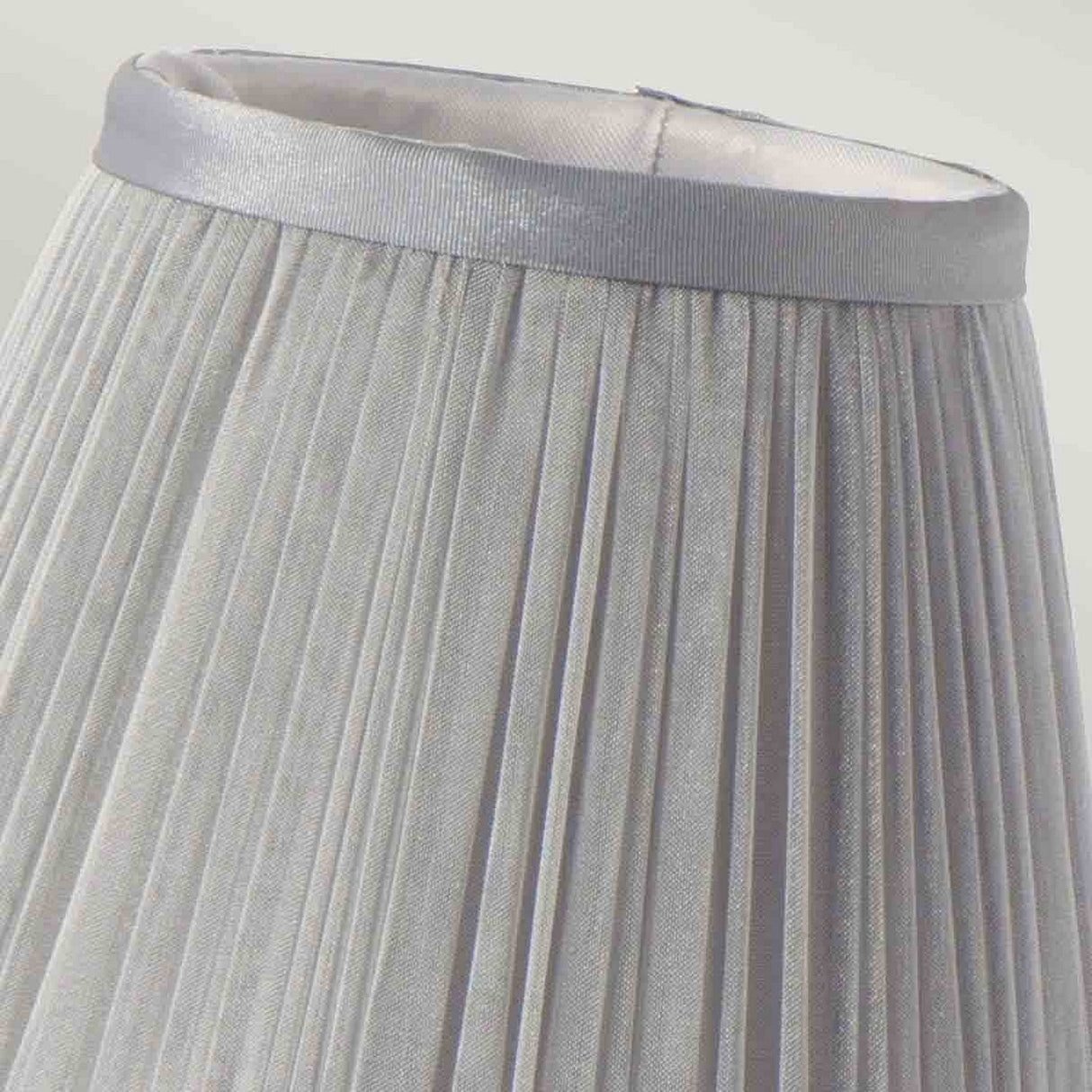 A close-up of the Clip Shades Pleated Grey Chiffon Candle Shade features a shiny silver trim at the top, showcasing its fabric texture and vertical pleats that lend it an elegant and classic appearance.